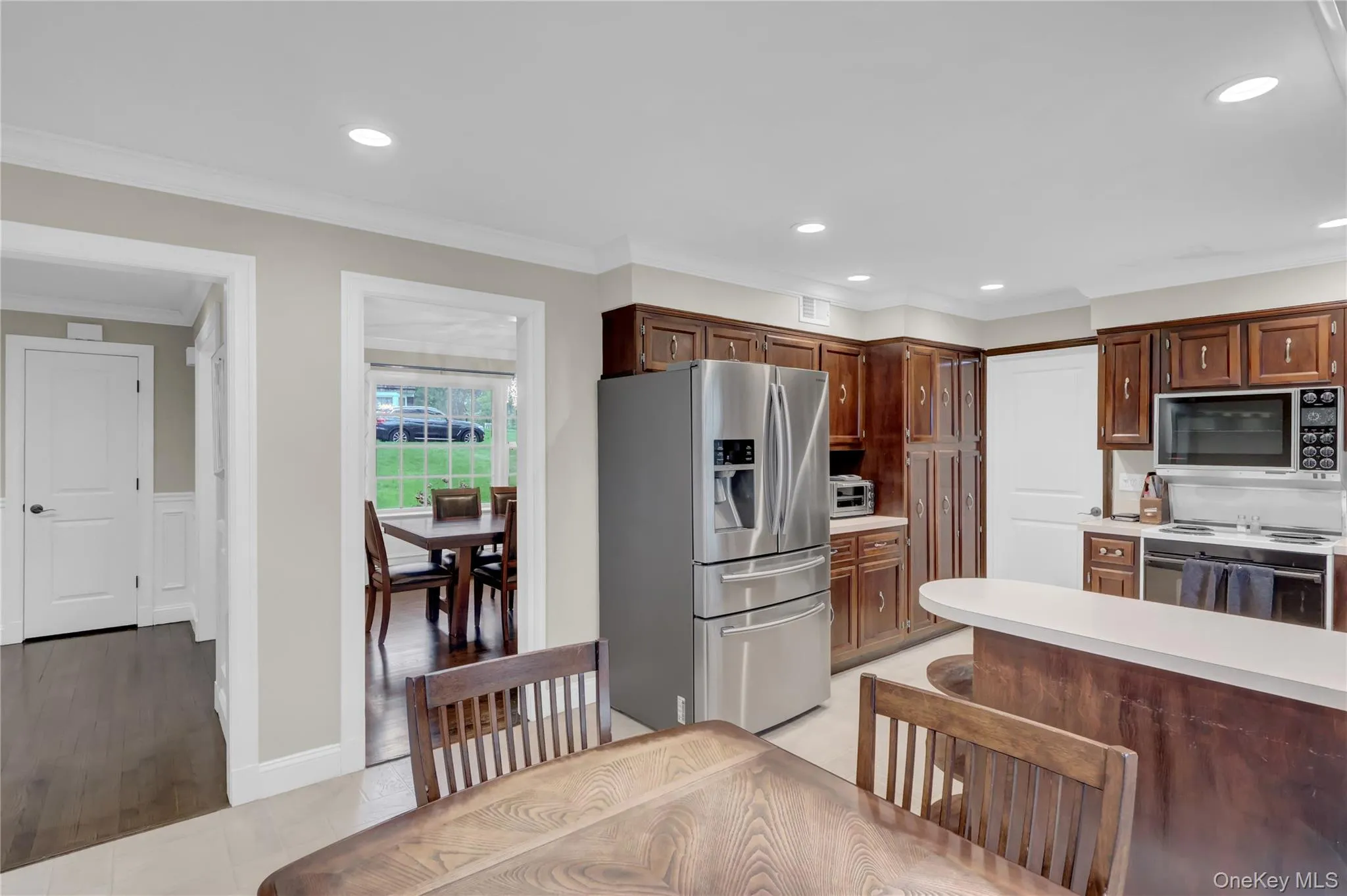 Kitchen featuring wood cabinetry, stainless steel appliances, and a breakfast bar with light-toned countertop Kitchen featuring wood cabinetry, stainless steel appliances, and a breakfast bar with light-toned countertop