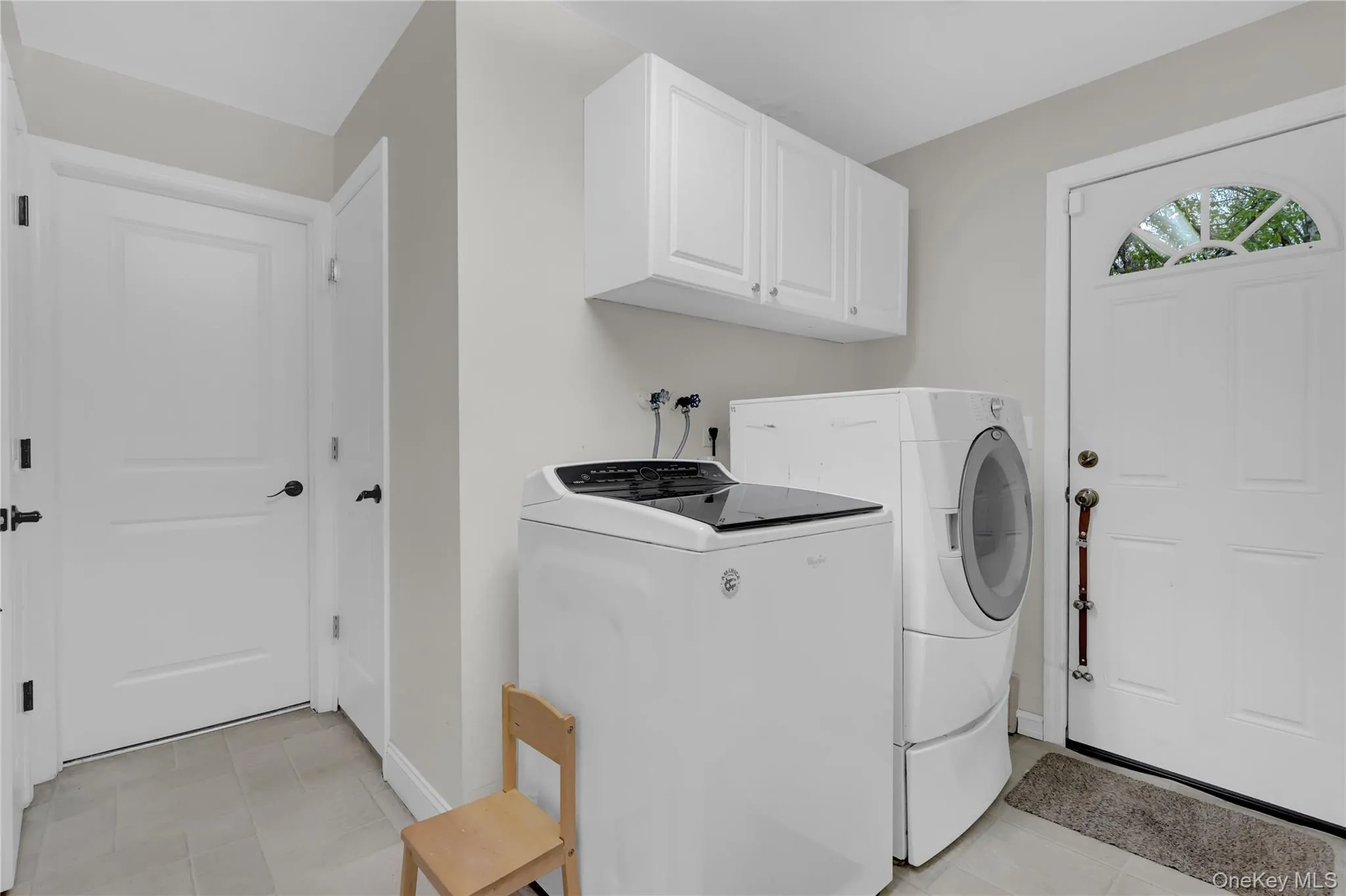 Laundry area featuring neutral wall paint and light-toned tile flooring Laundry area featuring neutral wall paint and light-toned tile flooring