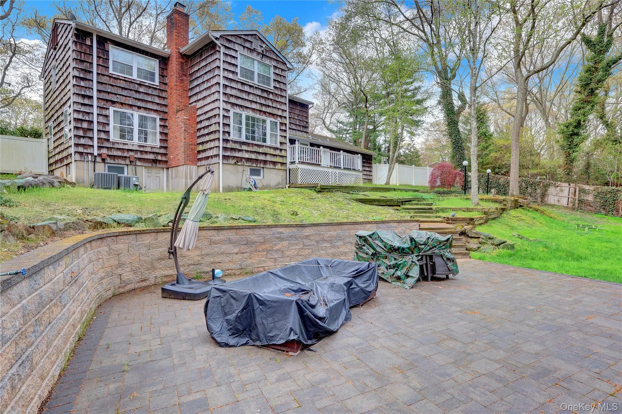 Expansive paver patio with a stone retaining wall and tiered landscaping Expansive paver patio with a stone retaining wall and tiered landscaping