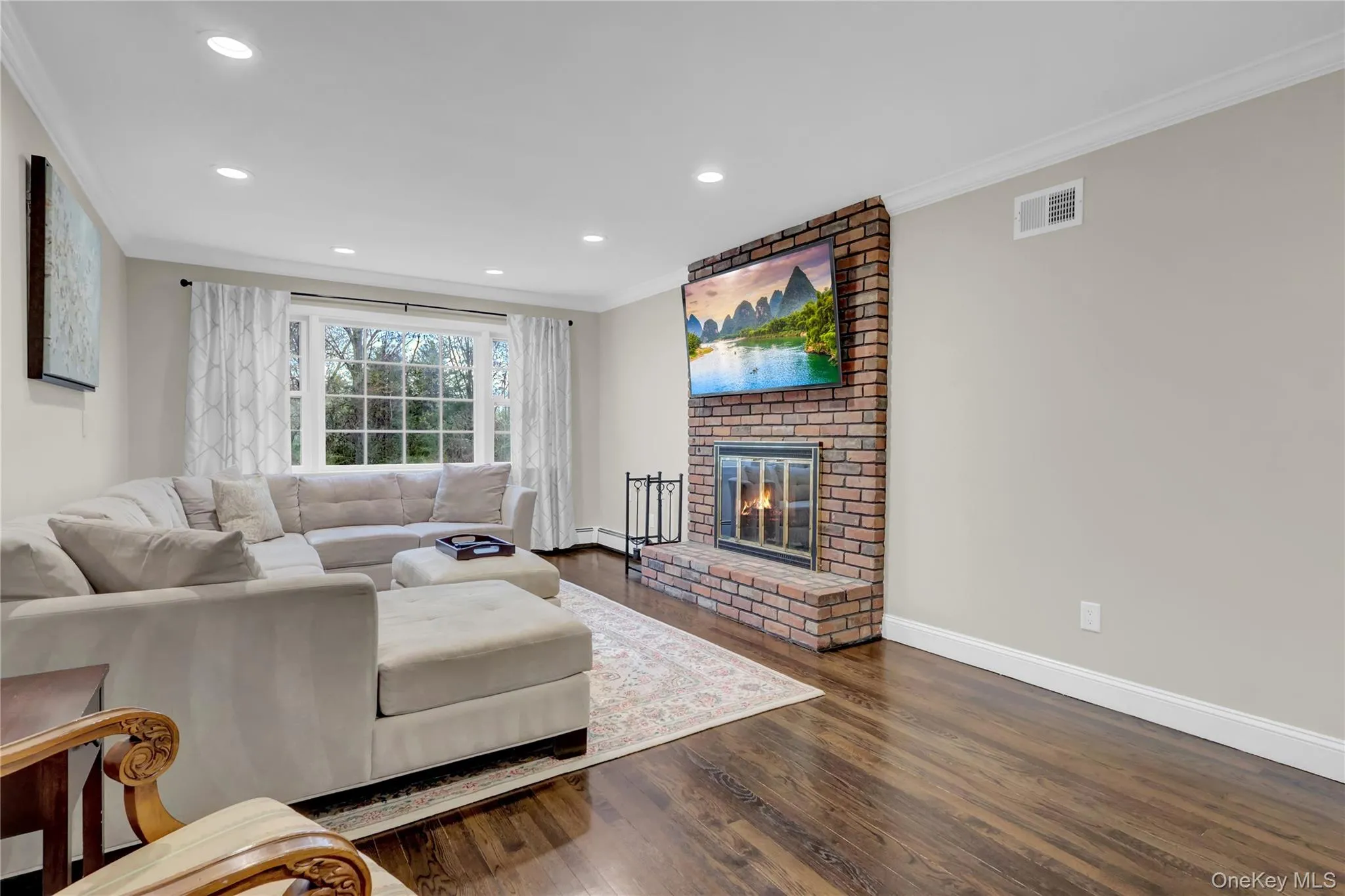 Living space featuring a brick-faced fireplace with a hearth and a large picture window Living space featuring a brick-faced fireplace with a hearth and a large picture window