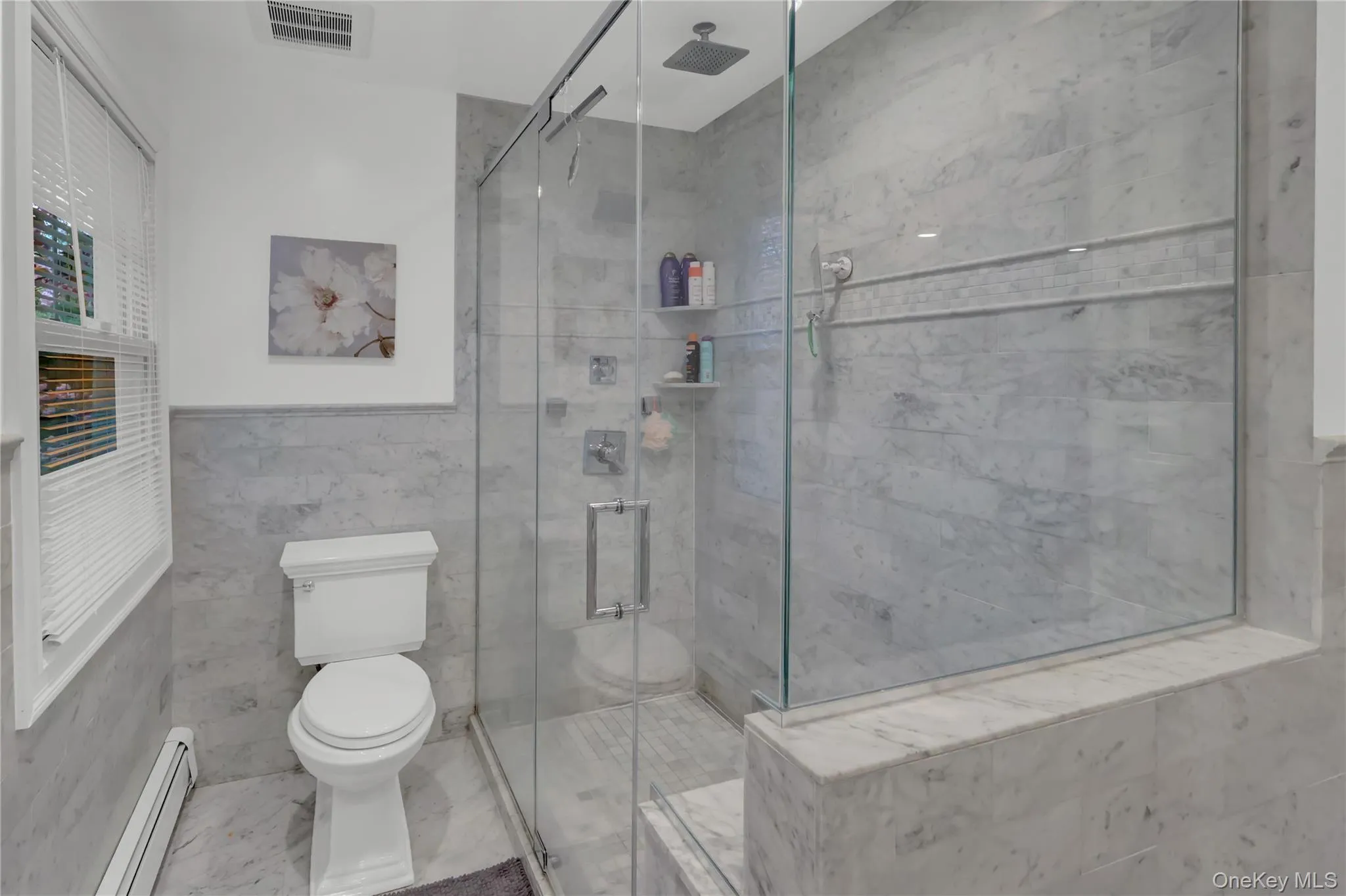 Shower enclosure featuring clear glass panels, a rainfall showerhead, and a tiled bench Shower enclosure featuring clear glass panels, a rainfall showerhead, and a tiled bench