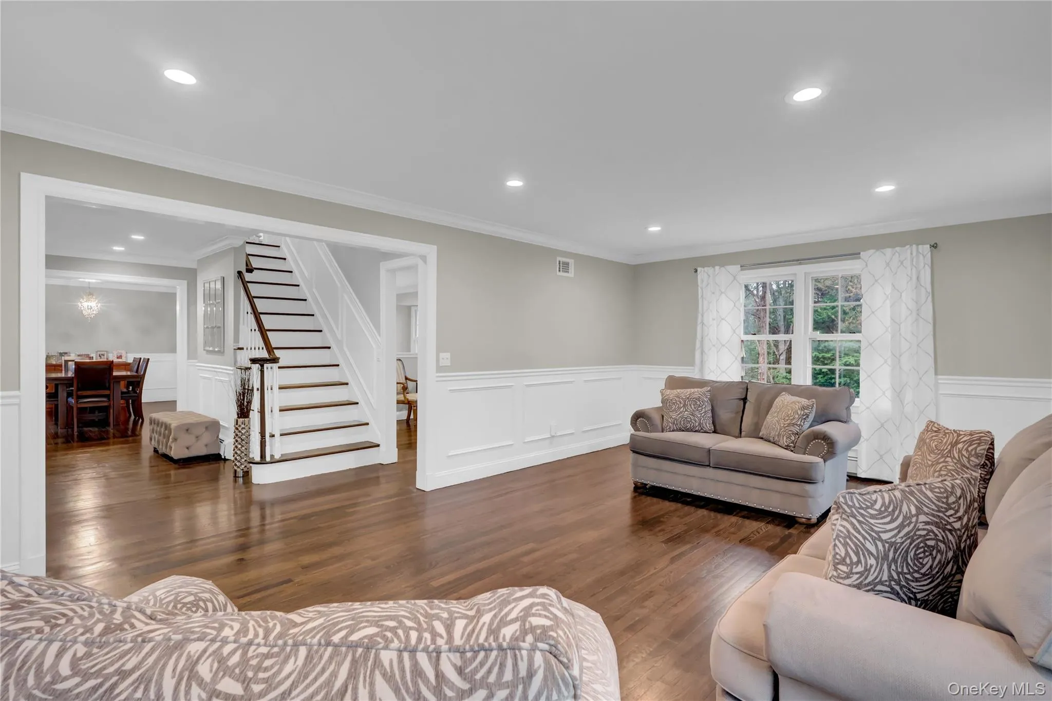 Spacious interior featuring wood-finish flooring, white wainscoting, and recessed lighting Spacious interior featuring wood-finish flooring, white wainscoting, and recessed lighting