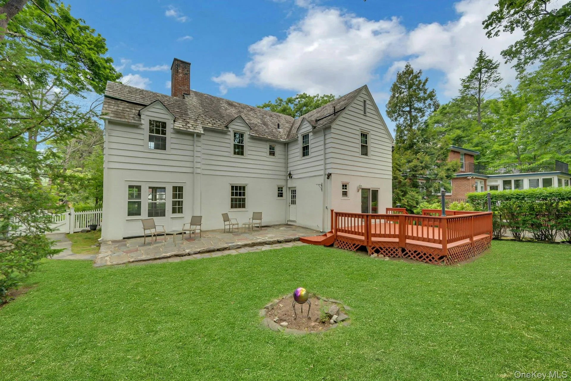 Rear exterior featuring slate roof, deck, and patio Rear exterior featuring slate roof, deck, and patio