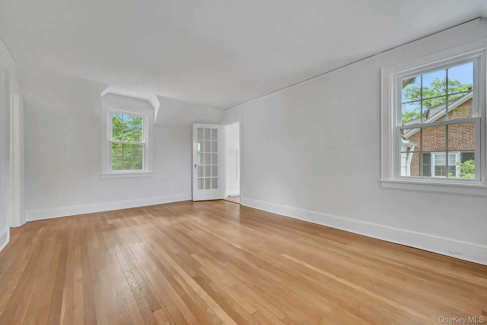 Primary bedroom with front and rear windows and French door to bonus room Primary bedroom with front and rear windows and French door to bonus room