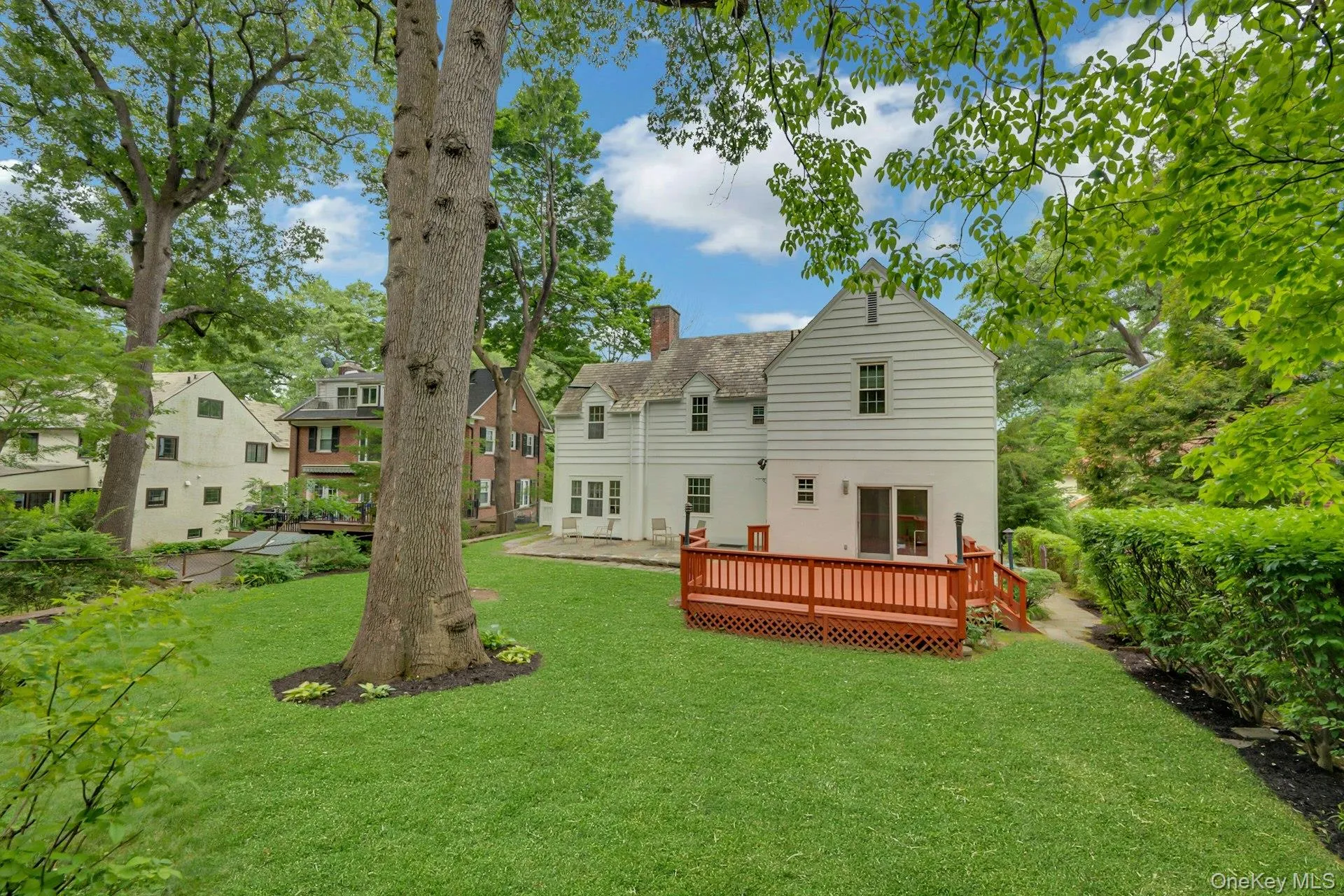 Rear yard view showcasing home, mature oak tree, and deck Rear yard view showcasing home, mature oak tree, and deck