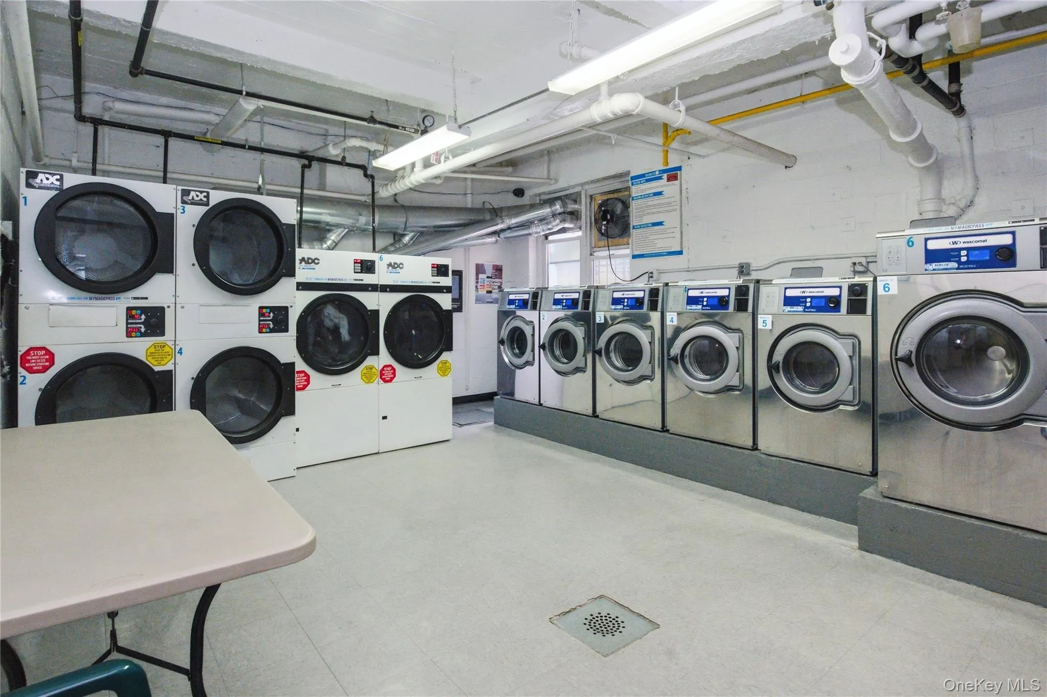 On-site laundry room featuring a selection of front-loading washers and dryers, along with a table for convenience On-site laundry room featuring a selection of front-loading washers and dryers, along with a table for convenience