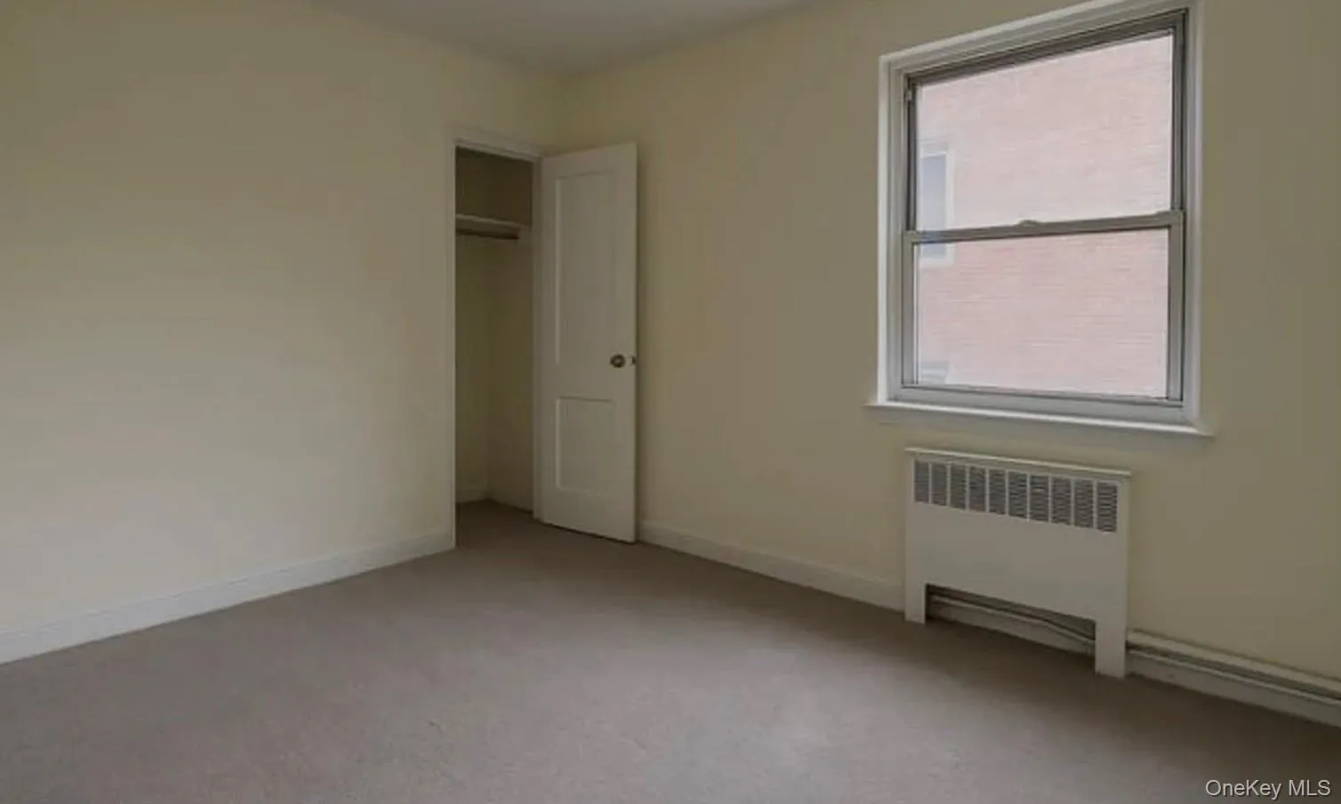 Unfurnished bedroom with radiator heating unit, a closet, and light colored carpet Unfurnished bedroom with radiator heating unit, a closet, and light colored carpet