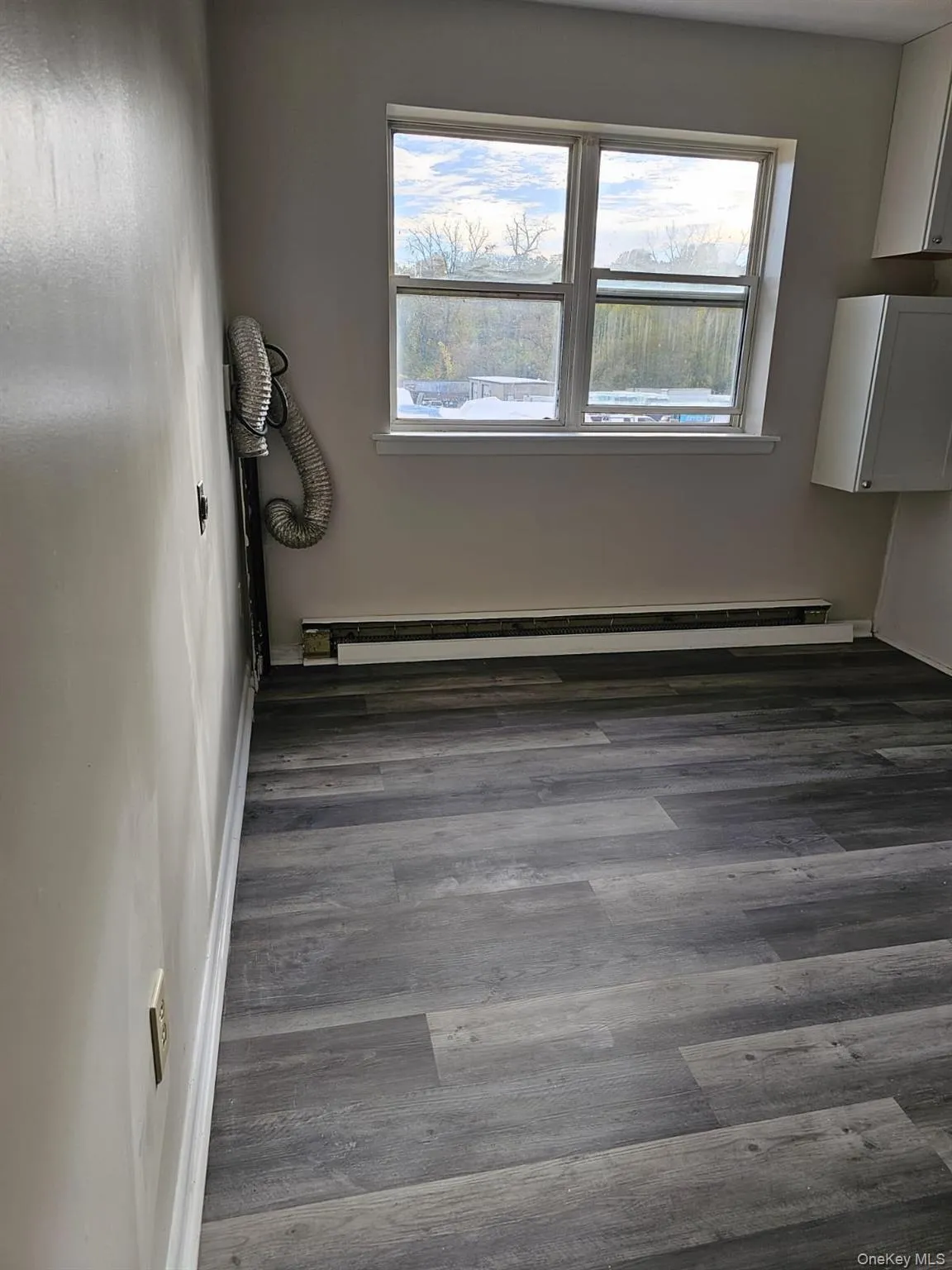 Unfurnished room featuring baseboard heating and wood finished floors Unfurnished room featuring baseboard heating and wood finished floors