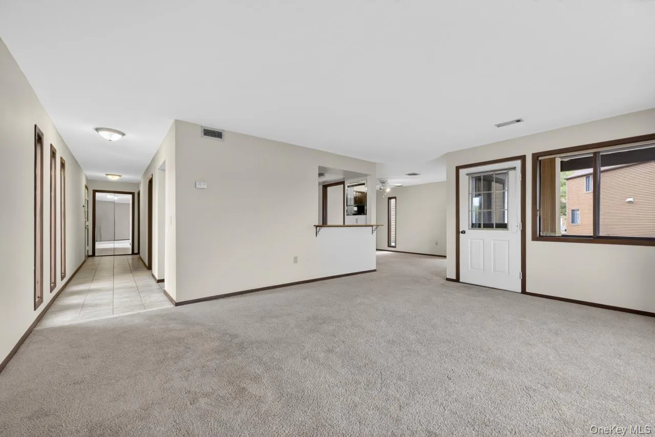 Open-concept living area featuring neutral carpeting and baseboards Open-concept living area featuring neutral carpeting and baseboards