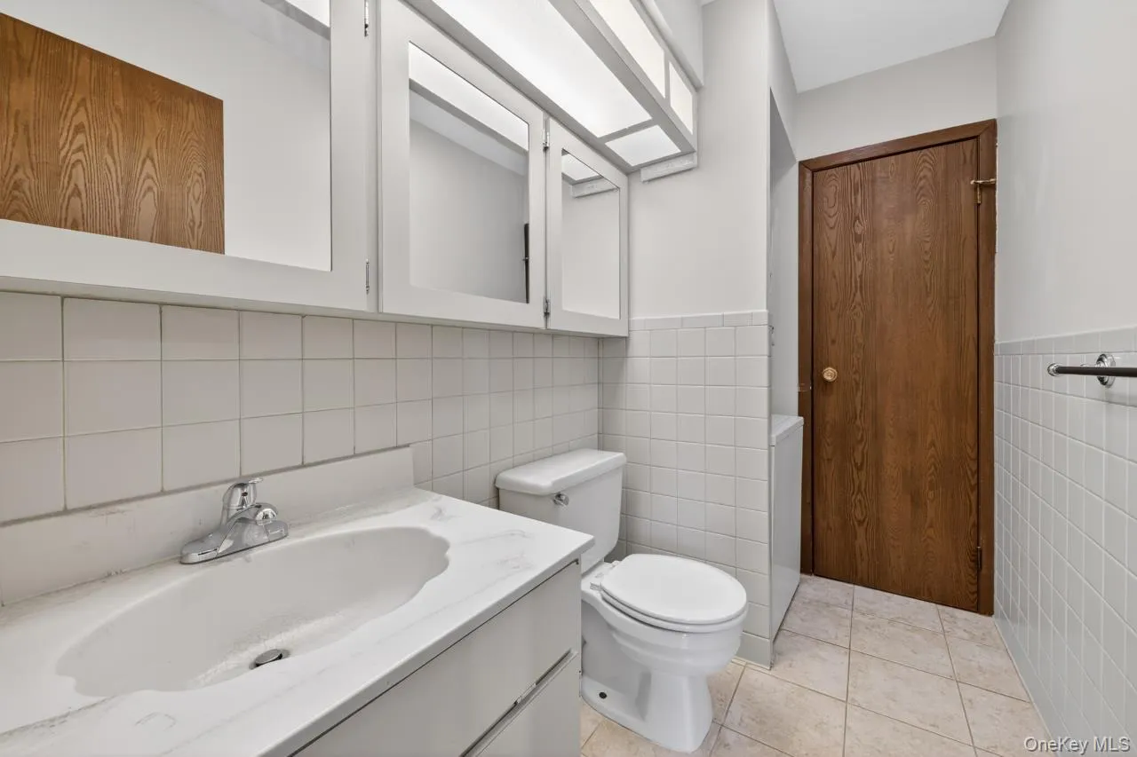 Bathroom featuring a white vanity with integrated sink, chrome faucet, and white upper cabinetry Bathroom featuring a white vanity with integrated sink, chrome faucet, and white upper cabinetry