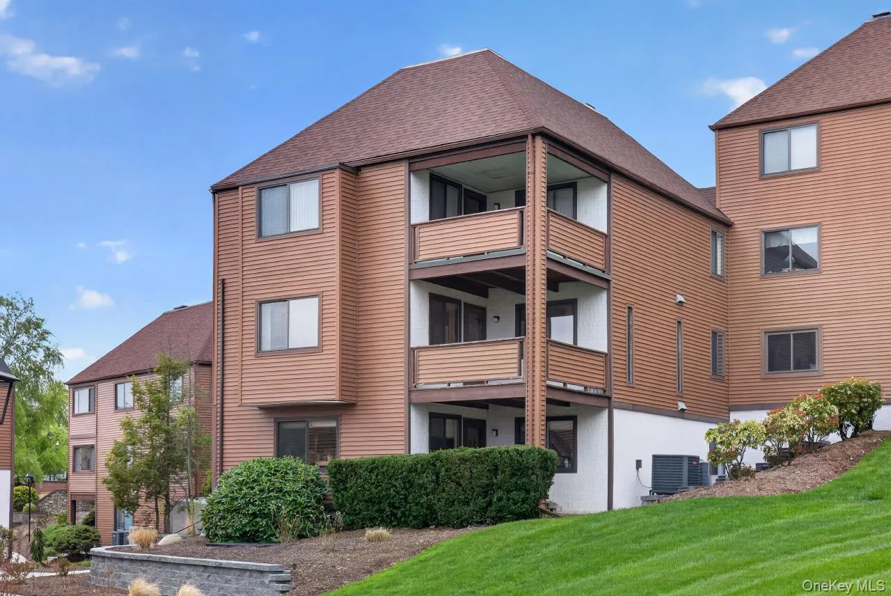 Multi-story residential building featuring balconies, brown siding, and pitched shingle roofs Multi-story residential building featuring balconies, brown siding, and pitched shingle roofs