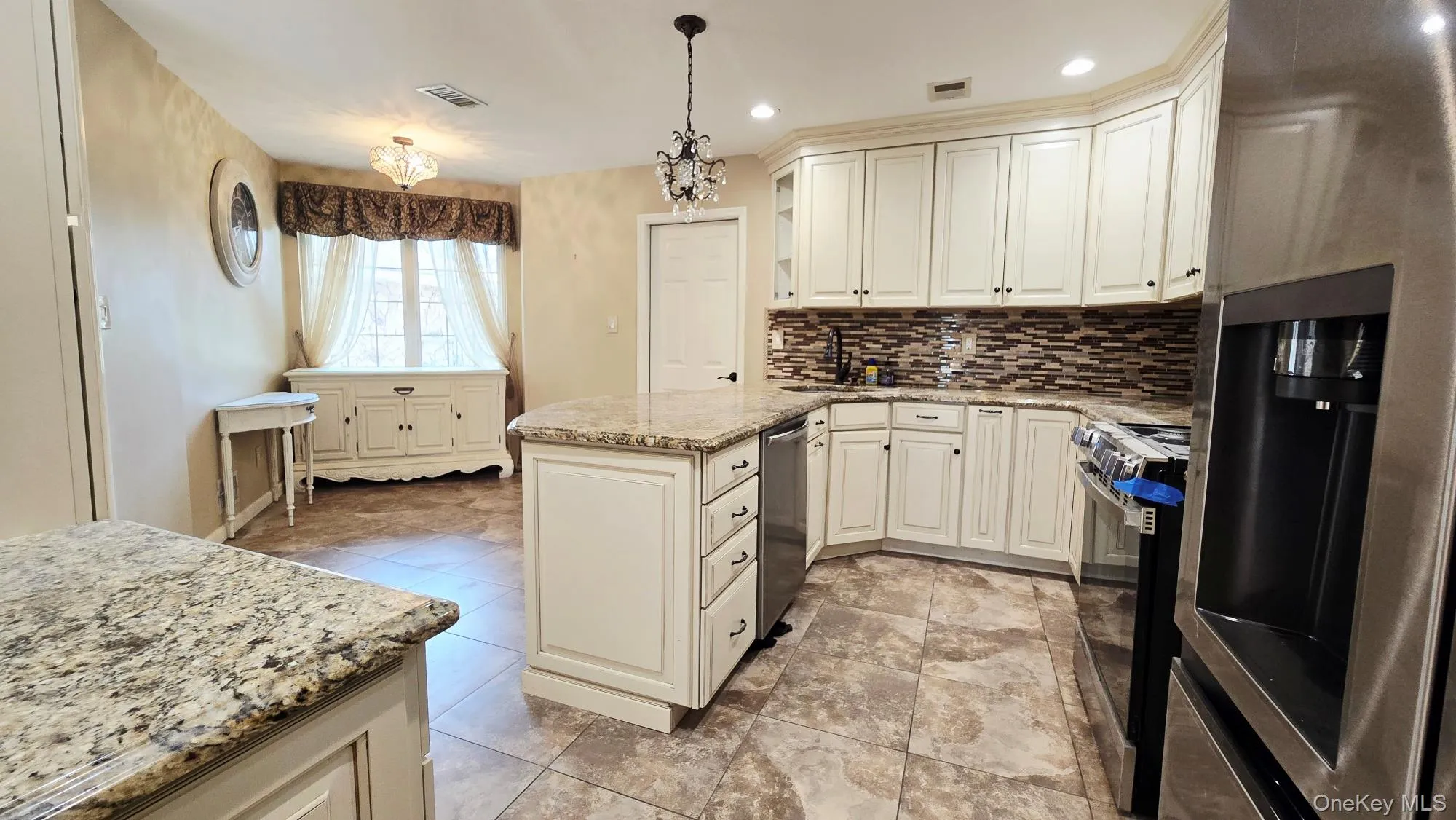 Kitchen featuring white cabinetry, granite countertops, a tiled backsplash, and stainless steel appliances Kitchen featuring white cabinetry, granite countertops, a tiled backsplash, and stainless steel appliances