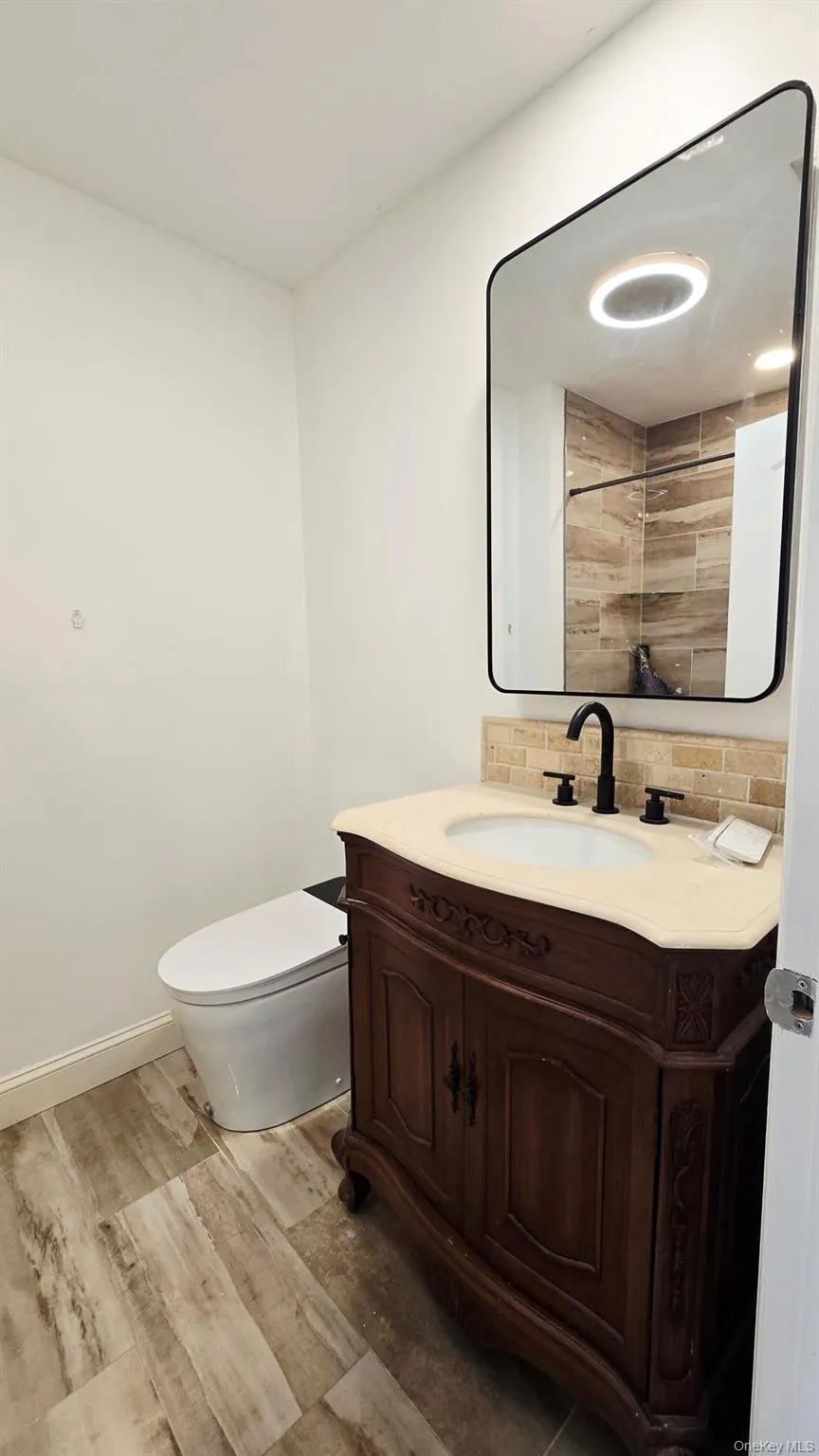 Full Bathroom on second floor featuring a dark wood vanity with a light-colored countertop, a rectangular mirror, a tub, and wood-look flooring Full Bathroom on second floor featuring a dark wood vanity with a light-colored countertop, a rectangular mirror, a tub, and wood-look flooring