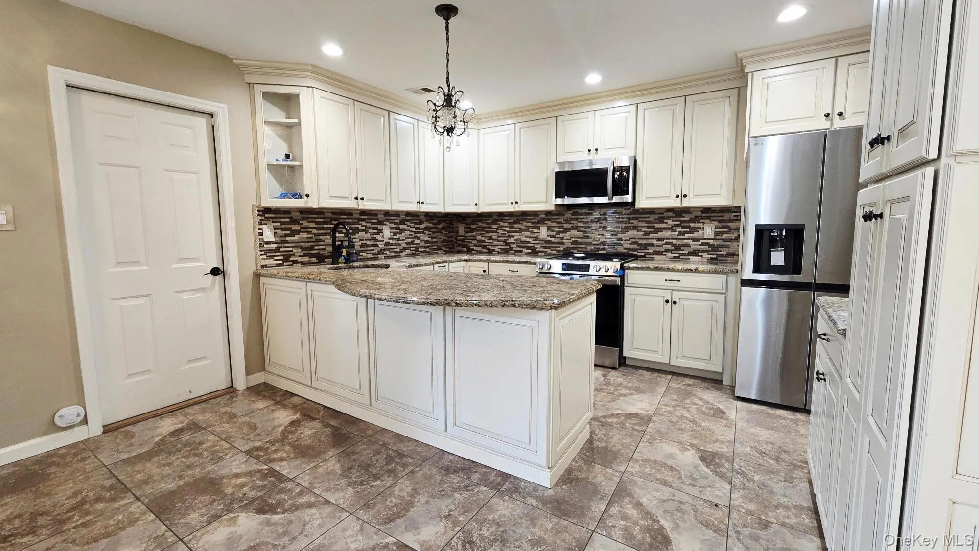 The property features a kitchen with white cabinetry, granite countertops, and a tiled backsplash The property features a kitchen with white cabinetry, granite countertops, and a tiled backsplash