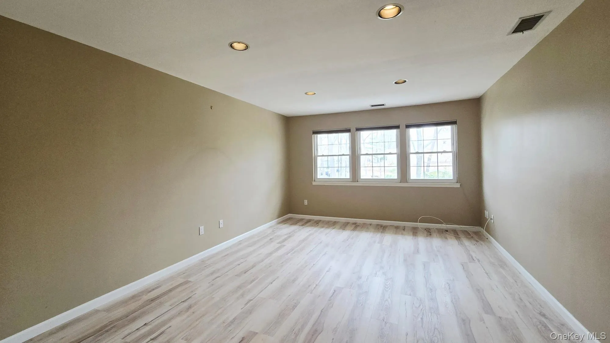 Primary Bedroom featuring light-toned flooring, recessed lighting, and three windows that provide natural light Primary Bedroom featuring light-toned flooring, recessed lighting, and three windows that provide natural light