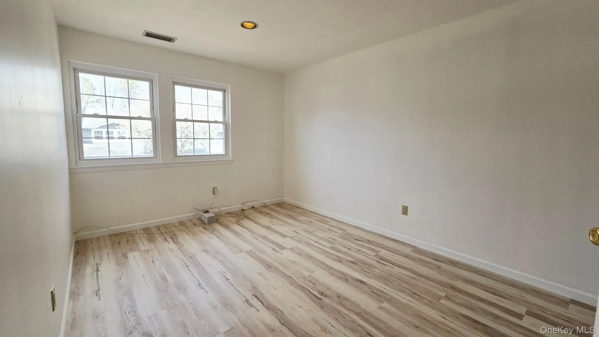 This room features light-colored plank flooring, two windows with white frames, and a ceiling light fixture This room features light-colored plank flooring, two windows with white frames, and a ceiling light fixture