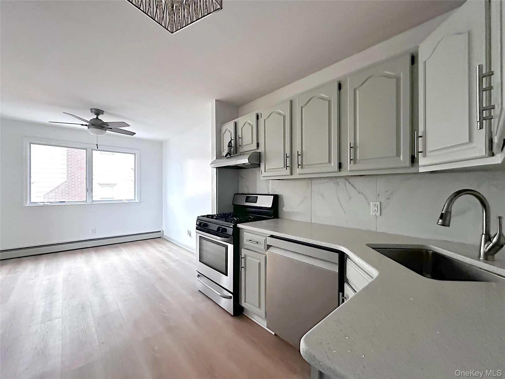 Kitchen featuring sink, gas stove, a baseboard radiator, dishwasher, and backsplash Kitchen featuring sink, gas stove, a baseboard radiator, dishwasher, and backsplash