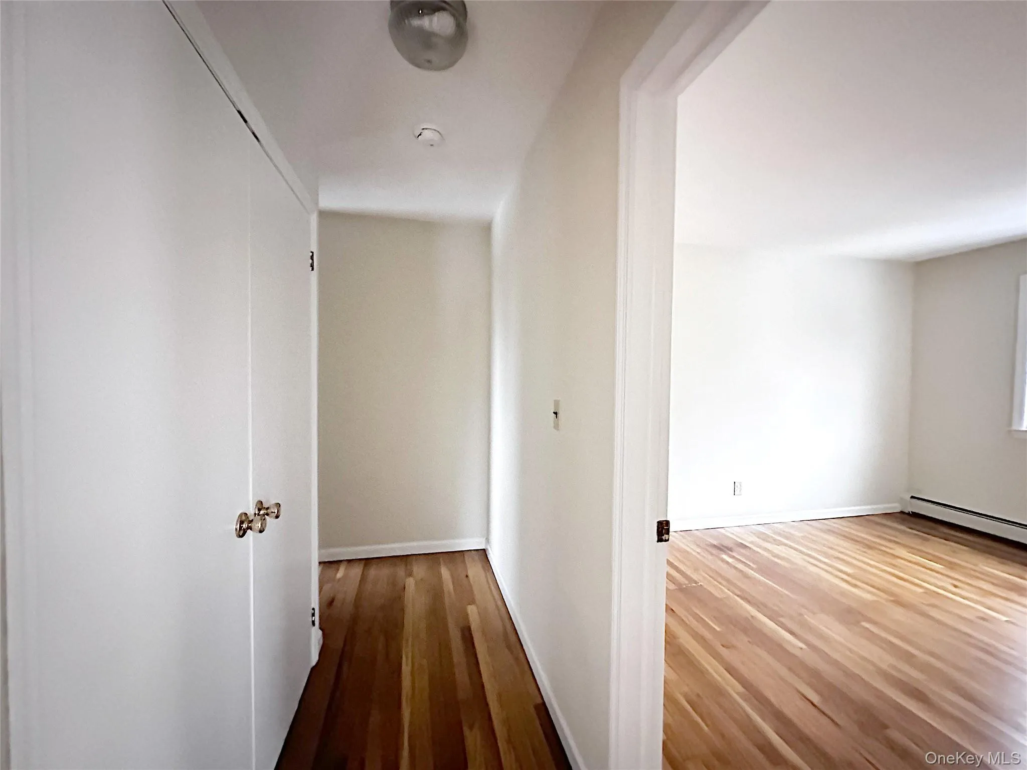 Corridor with wood-type flooring and a baseboard radiator Corridor with wood-type flooring and a baseboard radiator
