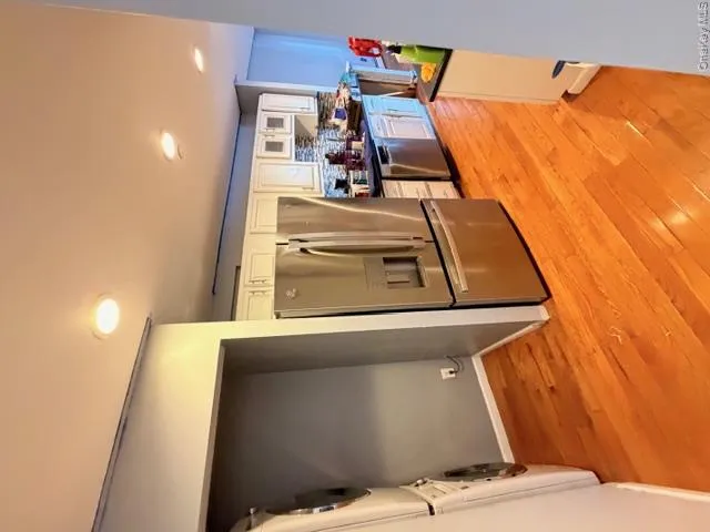 Kitchen featuring hardwood flooring, recessed lighting, white cabinetry with silver hardware, and stainless steel appliances Kitchen featuring hardwood flooring, recessed lighting, white cabinetry with silver hardware, and stainless steel appliances