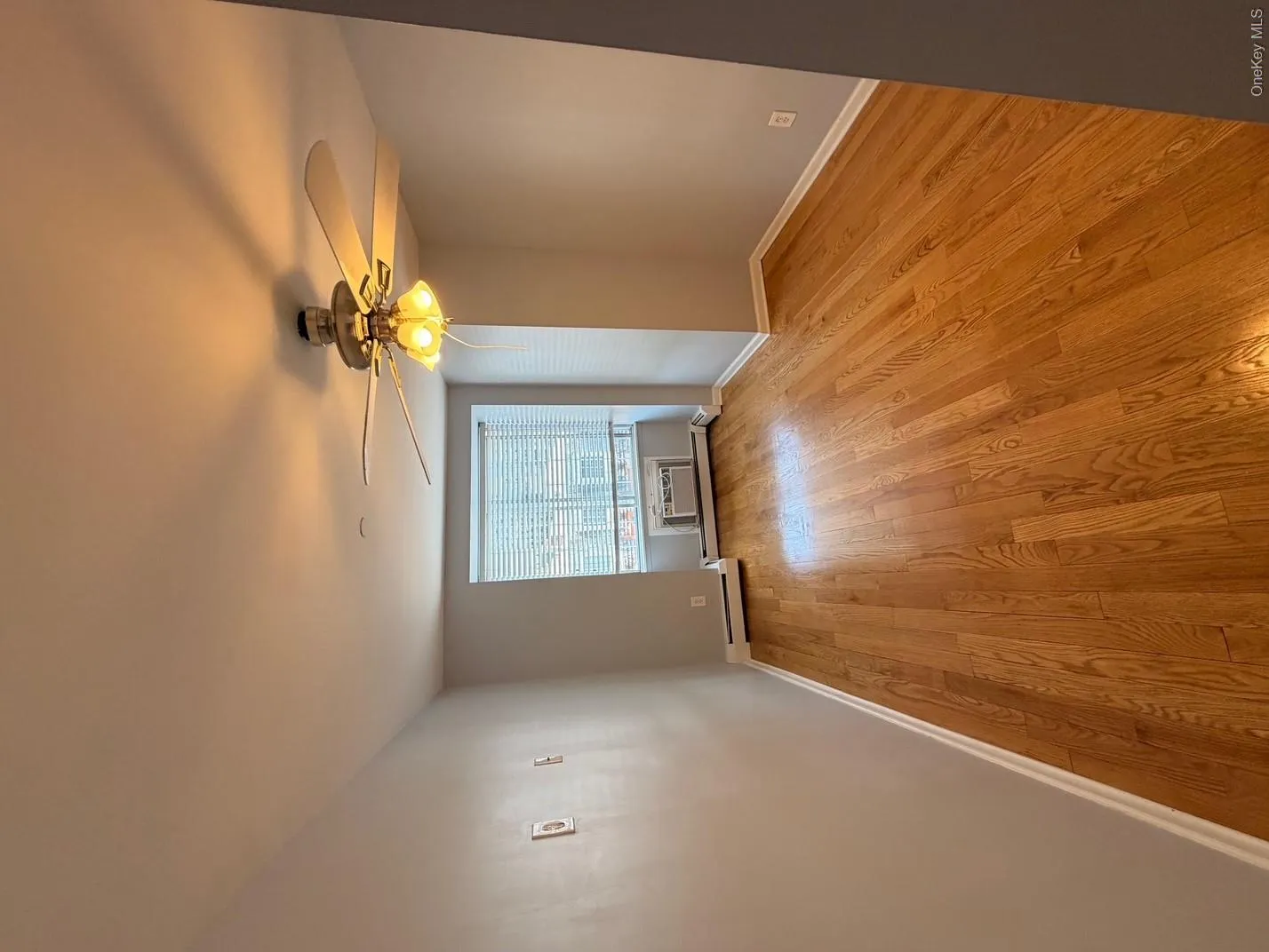 This room features hardwood floors, a window with blinds, and a ceiling fan with an integrated light fixture This room features hardwood floors, a window with blinds, and a ceiling fan with an integrated light fixture
