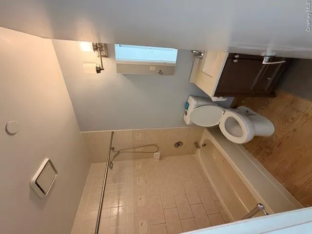 Bathroom featuring a shower and bathtub combination with tiled surround, a toilet, a vanity with a sink, and hardwood flooring Bathroom featuring a shower and bathtub combination with tiled surround, a toilet, a vanity with a sink, and hardwood flooring