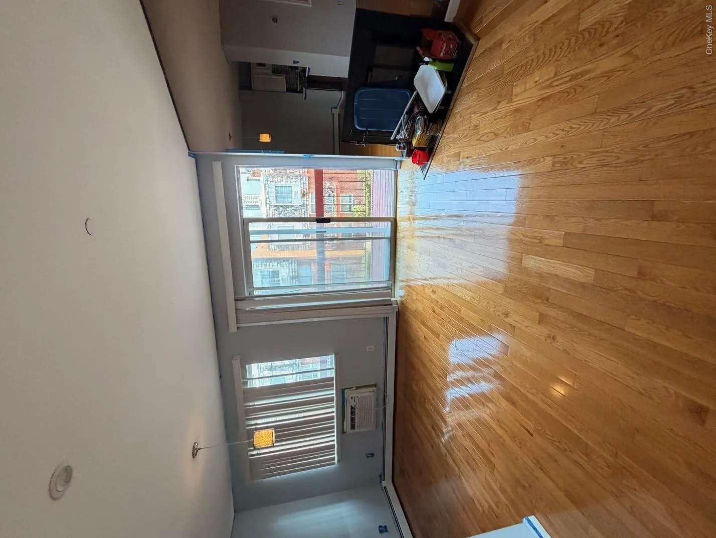 The living area features hardwood floors, a sliding glass door leading to an outdoor space, and a window with blinds The living area features hardwood floors, a sliding glass door leading to an outdoor space, and a window with blinds