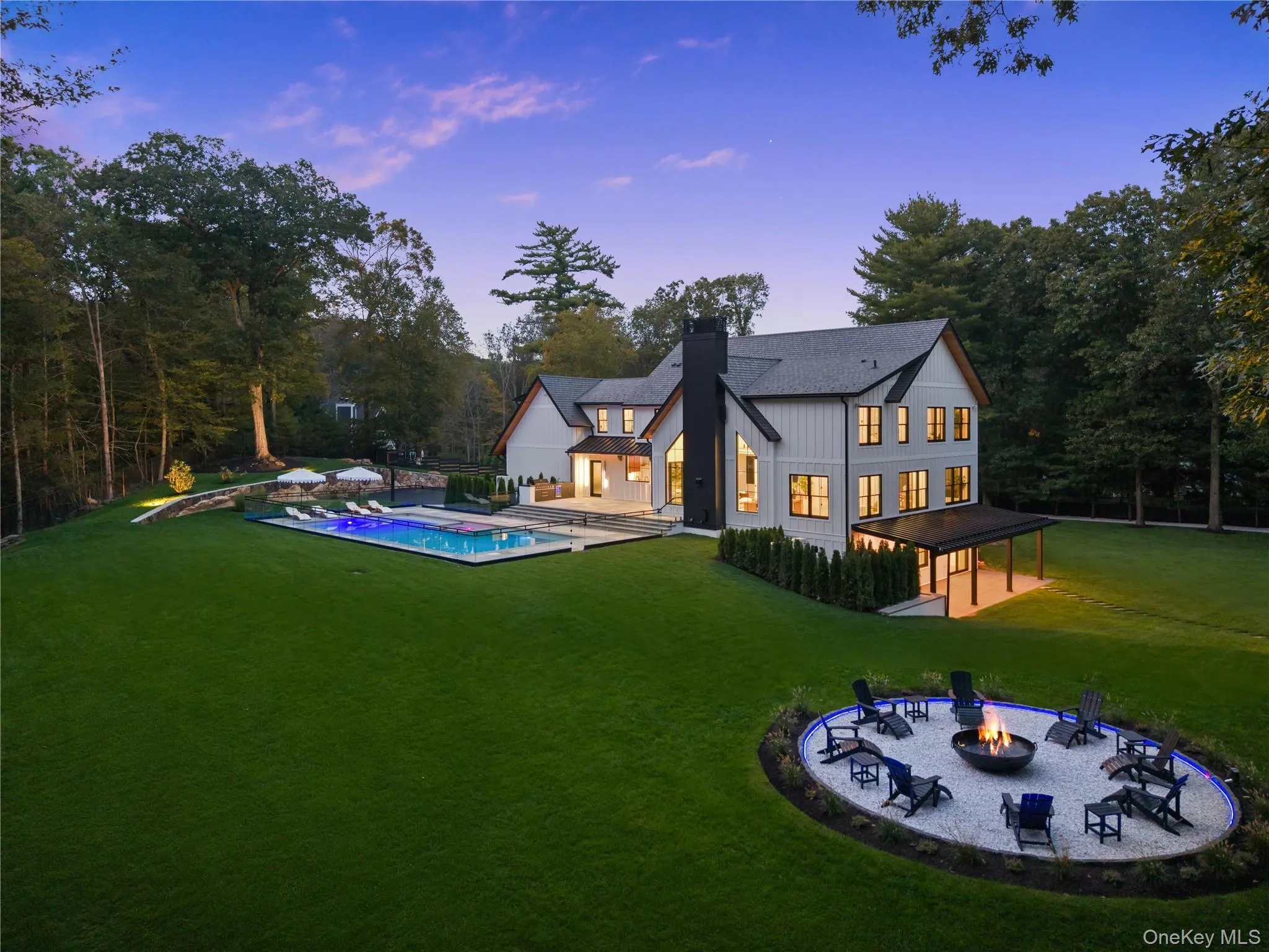 Back of property featuring a patio area, a fire pit, a lawn, a chimney, and board and batten siding Back of property featuring a patio area, a fire pit, a lawn, a chimney, and board and batten siding