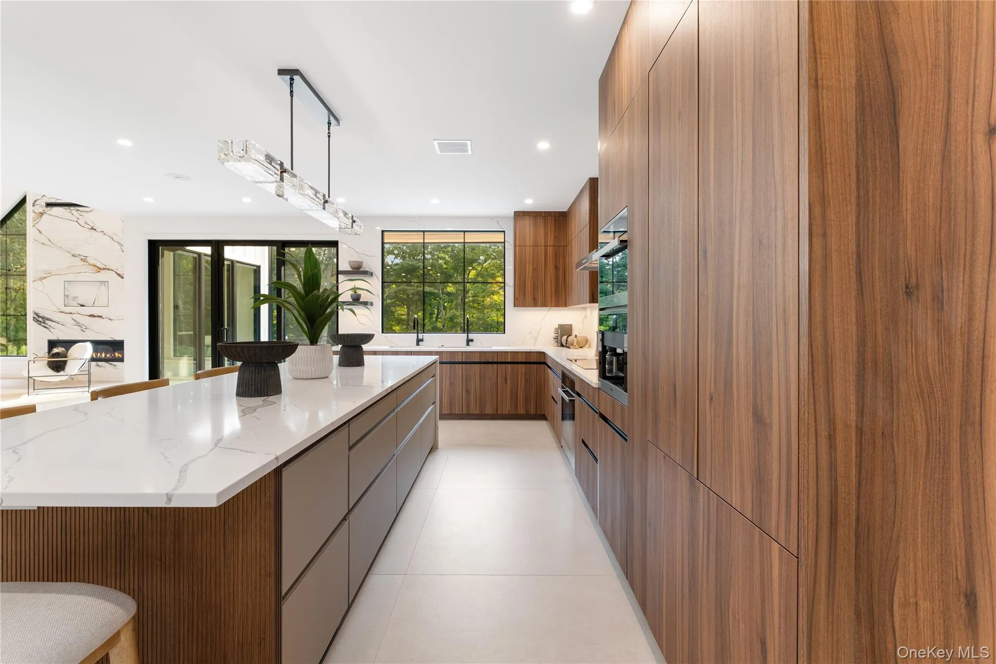 Kitchen featuring modern cabinets, hanging light fixtures, light stone counters, a spacious island, and a kitchen bar Kitchen featuring modern cabinets, hanging light fixtures, light stone counters, a spacious island, and a kitchen bar