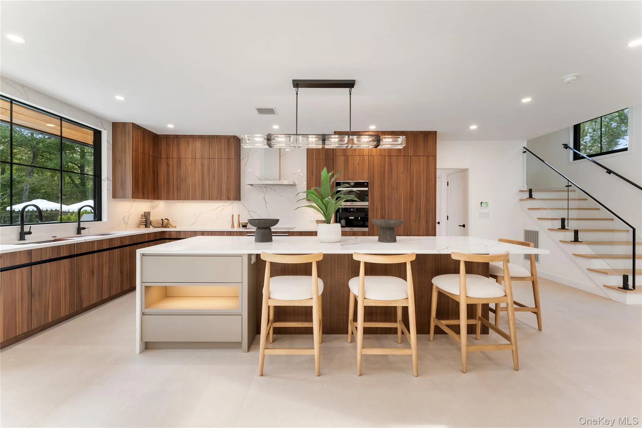 Kitchen featuring brown cabinetry, modern cabinets, decorative backsplash, light stone counters, and decorative light fixtures Kitchen featuring brown cabinetry, modern cabinets, decorative backsplash, light stone counters, and decorative light fixtures