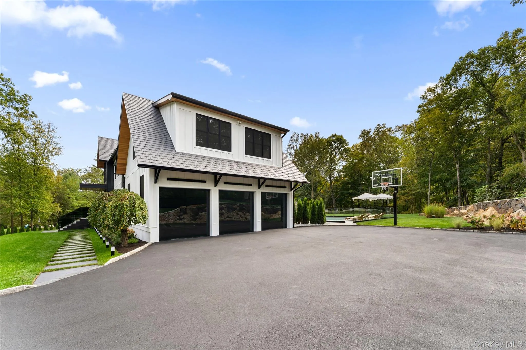 Three car garage attached to side of home with basketball hoop in long private driveway. Three car garage attached to side of home with basketball hoop in long private driveway.