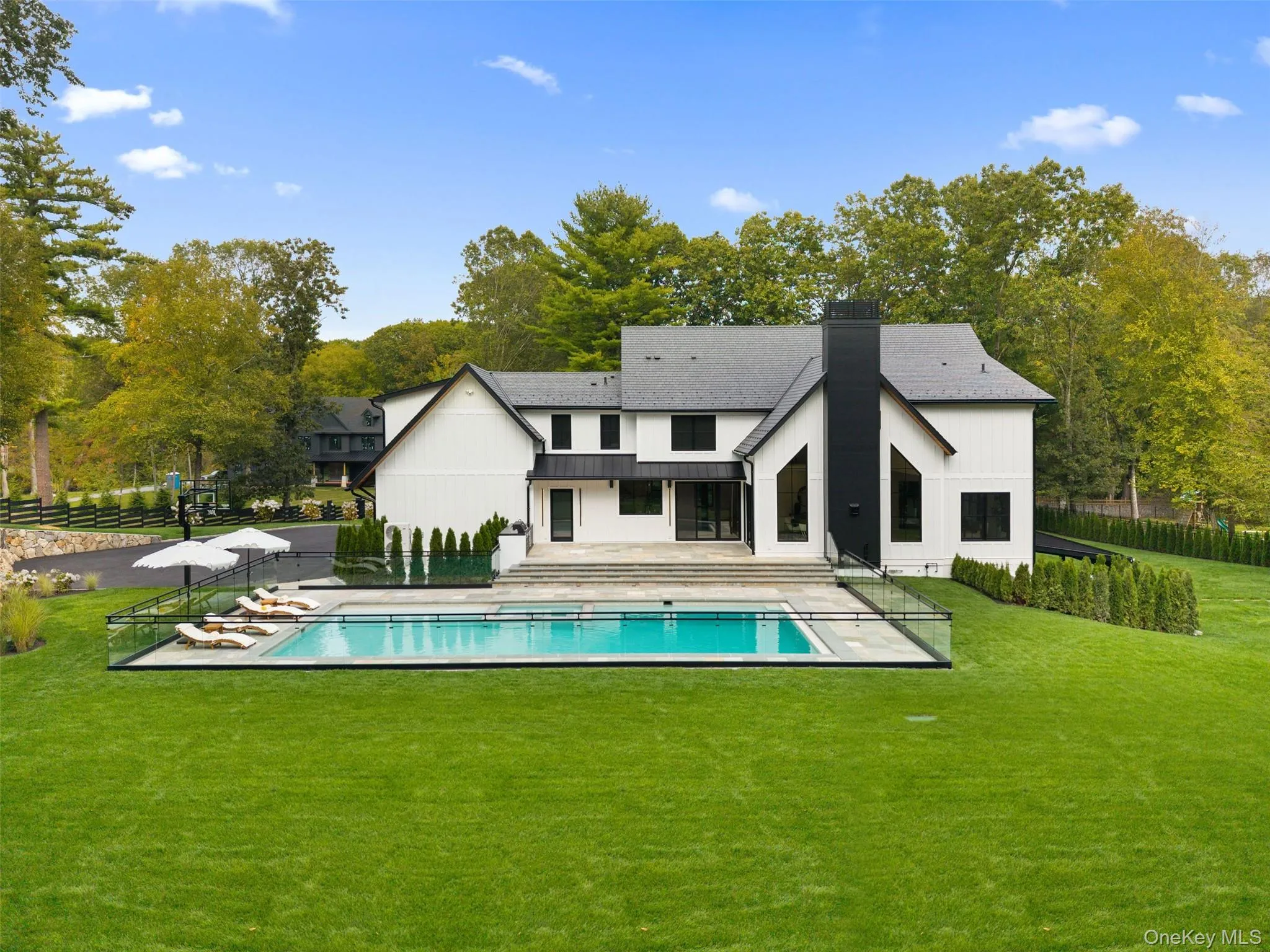 Back of property featuring a patio, a chimney, view of scattered trees, and a metal roof Back of property featuring a patio, a chimney, view of scattered trees, and a metal roof