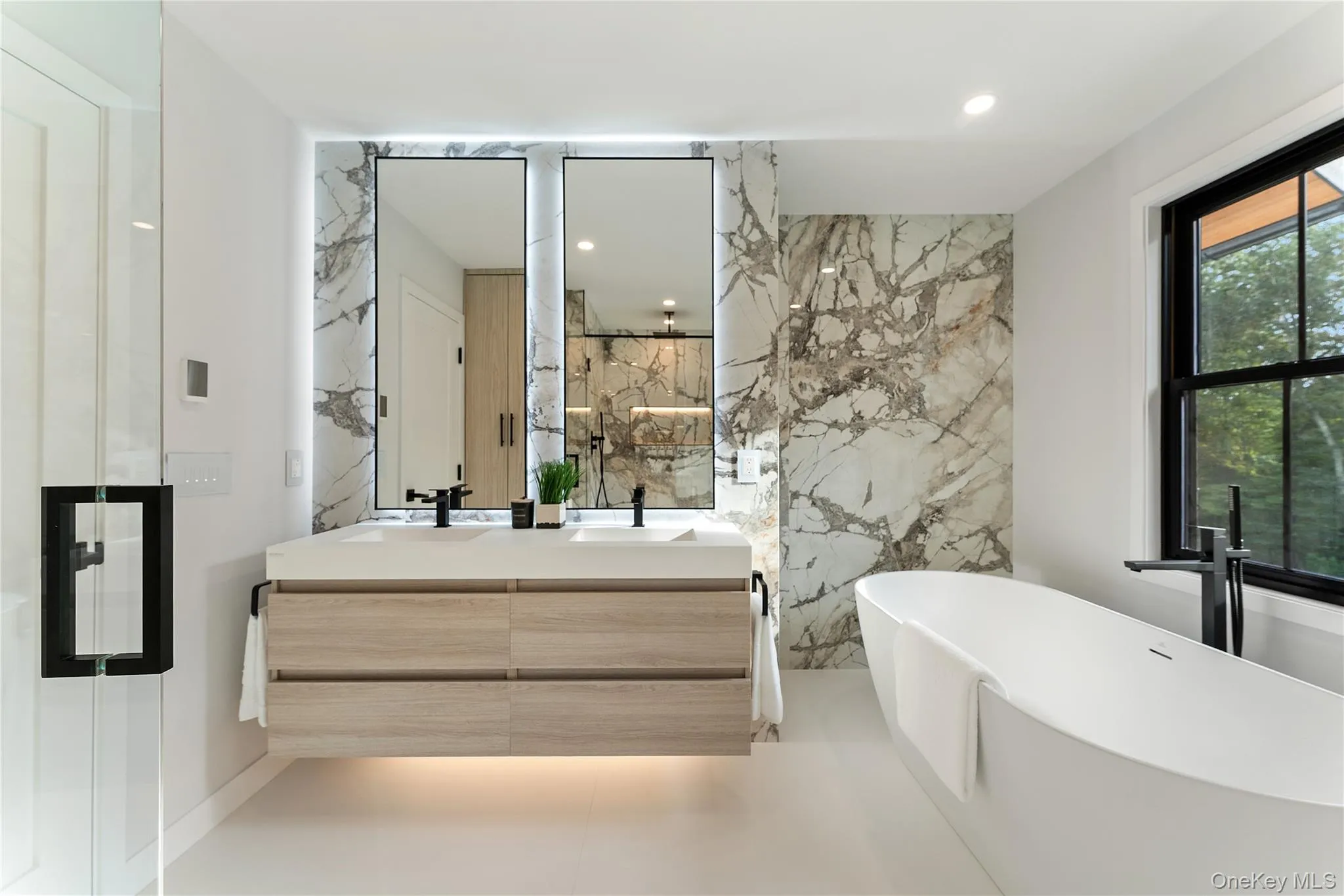 Full bathroom featuring double vanity, a freestanding bath, stone wall, and recessed lighting Full bathroom featuring double vanity, a freestanding bath, stone wall, and recessed lighting