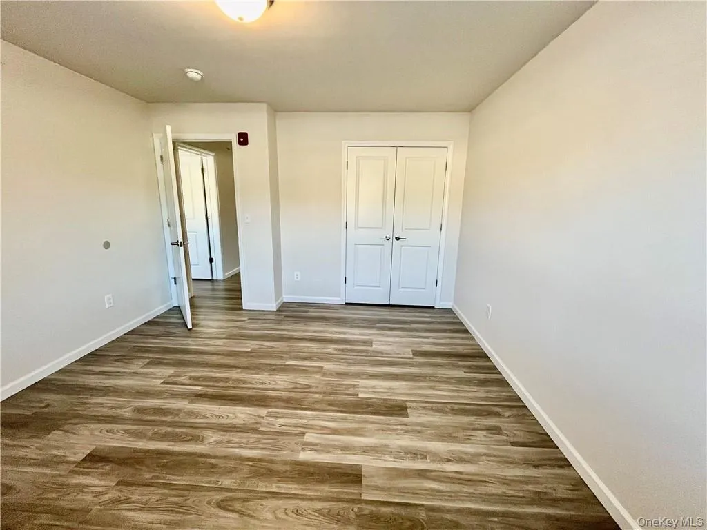 Unfurnished bedroom featuring dark wood-type flooring and a closet Unfurnished bedroom featuring dark wood-type flooring and a closet