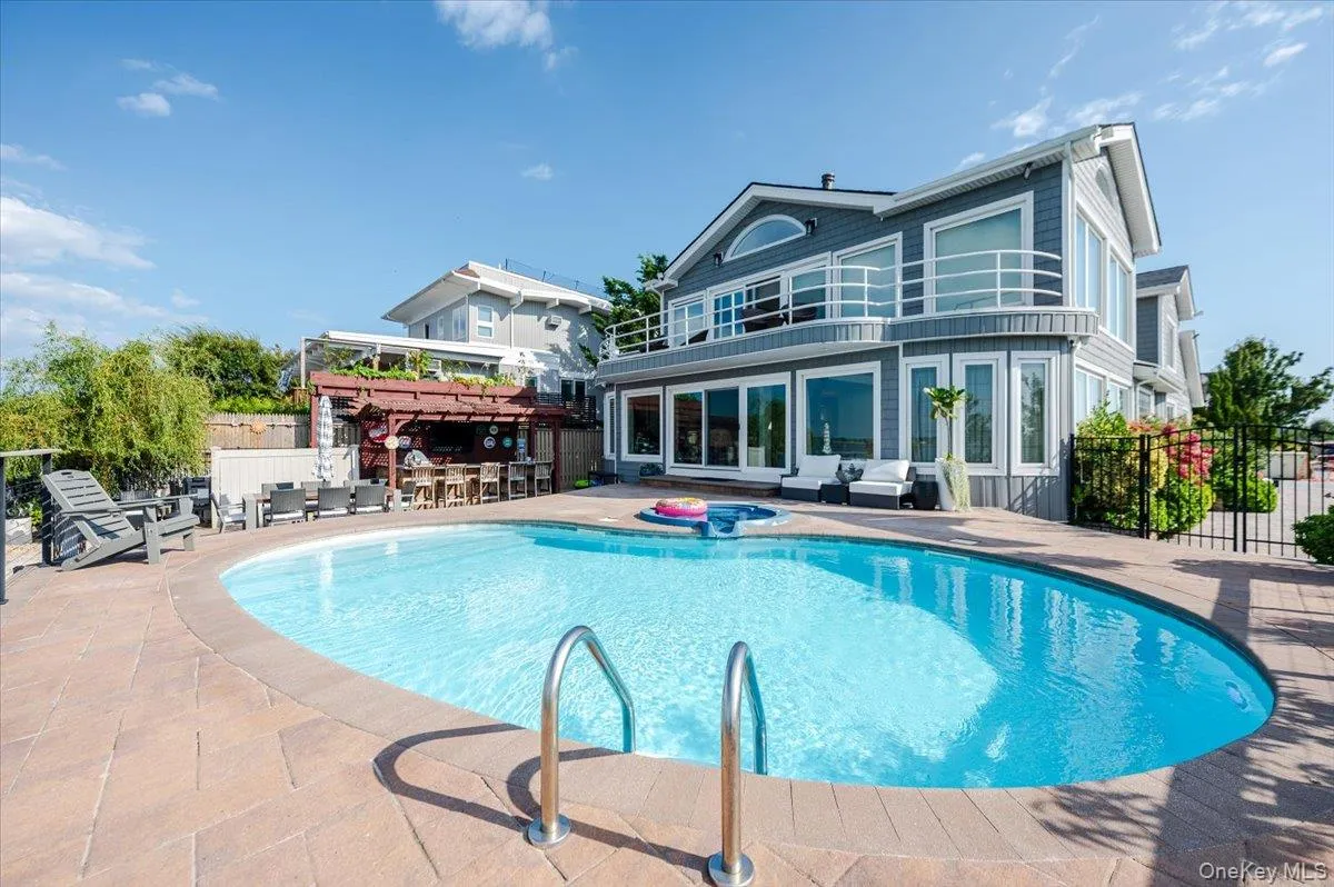 Rear view of house featuring a patio, an in-ground hot tub, and a balcony Rear view of house featuring a patio, an in-ground hot tub, and a balcony