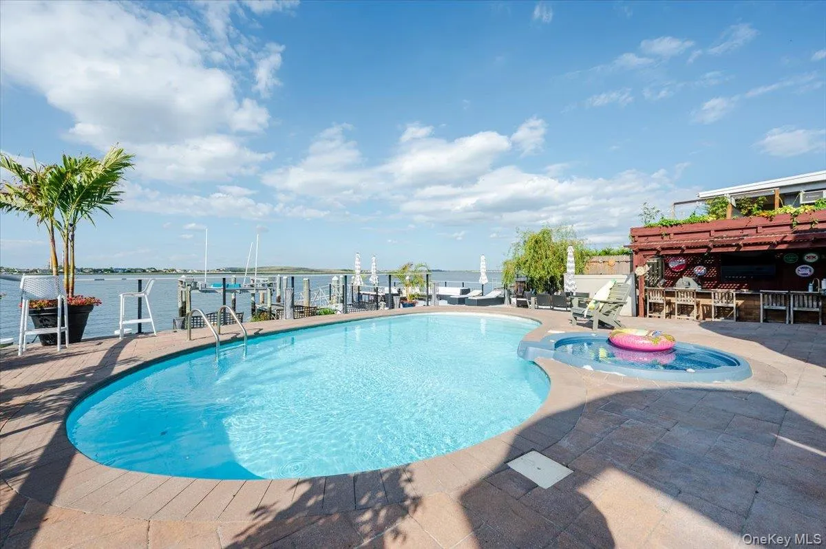 View of pool featuring a water view, a jacuzzi, and a patio area View of pool featuring a water view, a jacuzzi, and a patio area