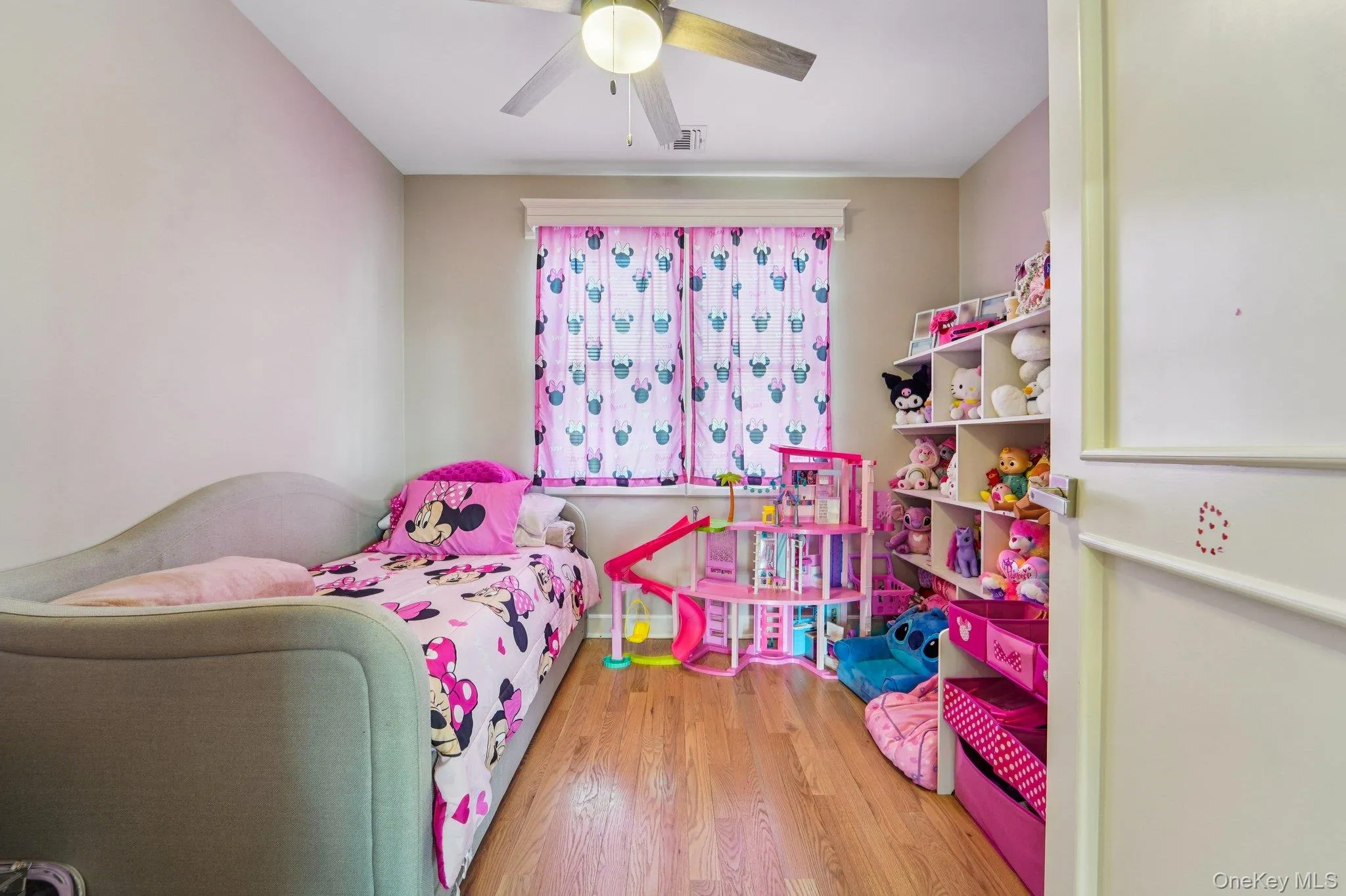 Bedroom 4: This room features hardwood flooring, a window with patterned curtains, and a ceiling fan with integrated lighting. Bedroom 4: This room features hardwood flooring, a window with patterned curtains, and a ceiling fan with integrated lighting.