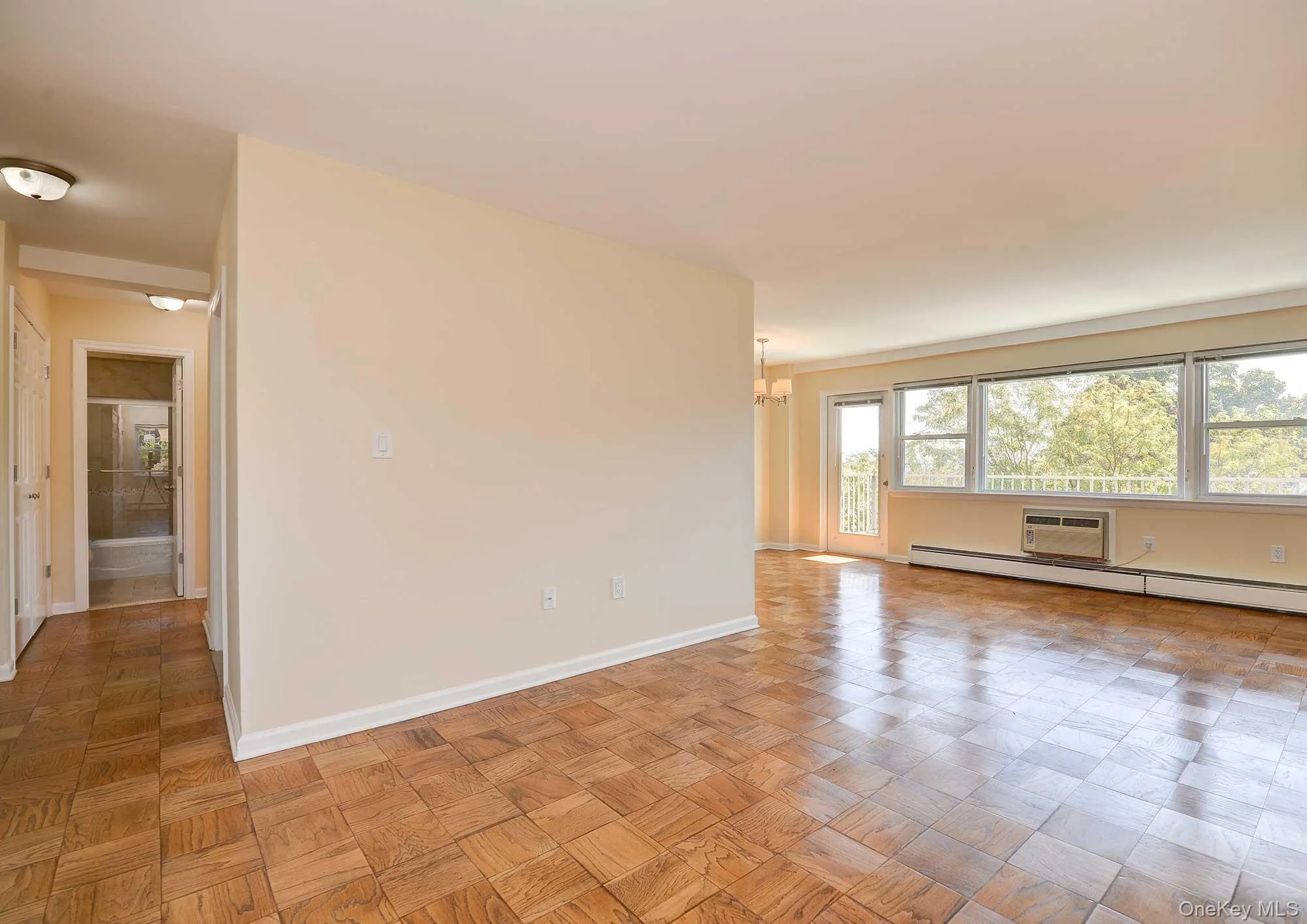 Bright living space featuring parquet flooring, large windows, and a door leading to an outdoor area Bright living space featuring parquet flooring, large windows, and a door leading to an outdoor area