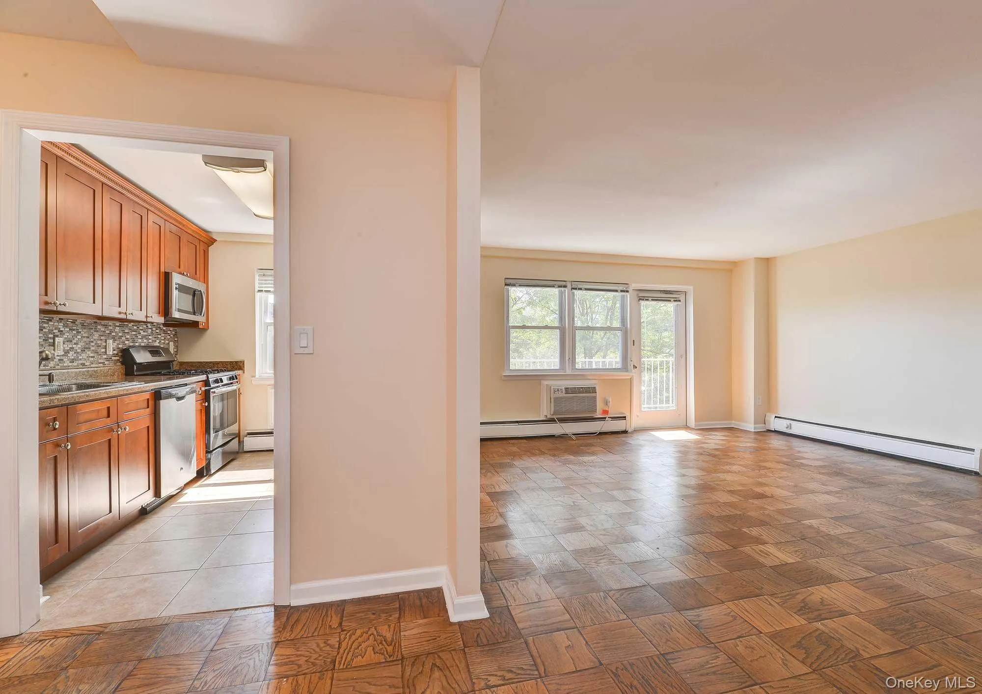 The living area features parquet flooring, a large window, and access to a balcony The living area features parquet flooring, a large window, and access to a balcony