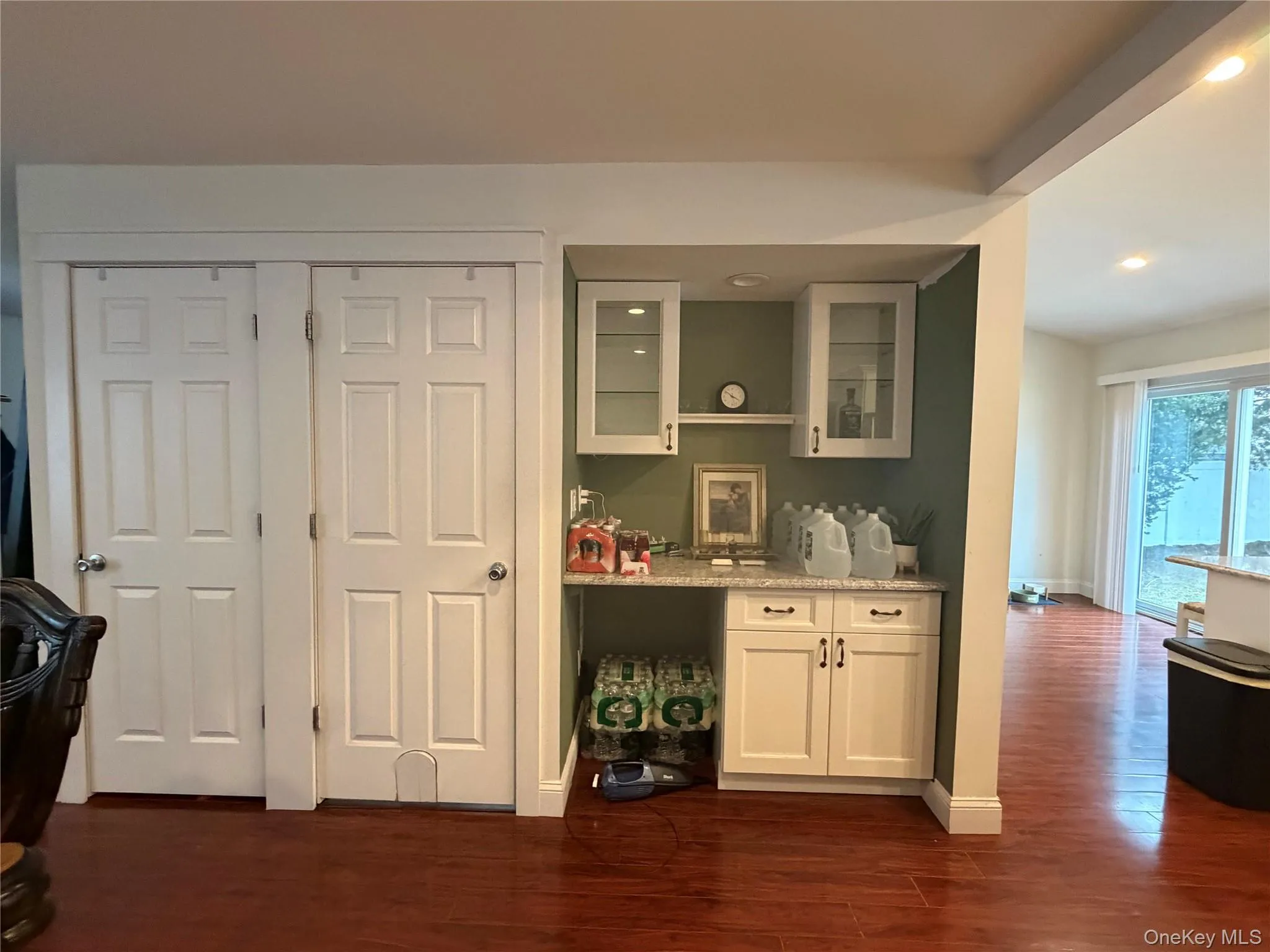 This space features rich hardwood flooring, built-in cabinetry with a granite countertop, and glass-front upper cabinets This space features rich hardwood flooring, built-in cabinetry with a granite countertop, and glass-front upper cabinets