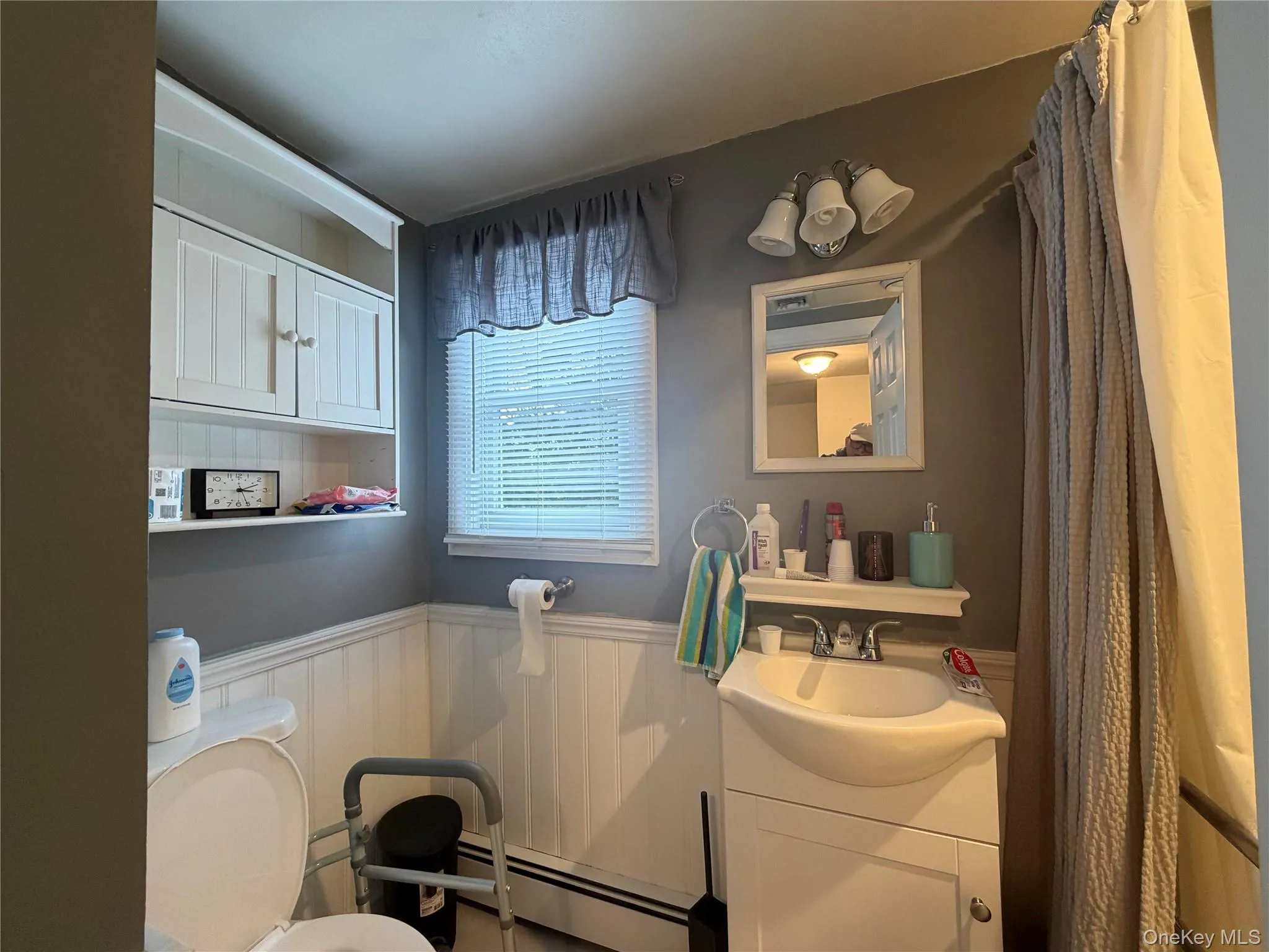 The bathroom includes a vanity with a sink, a mirror, and overhead lighting The bathroom includes a vanity with a sink, a mirror, and overhead lighting