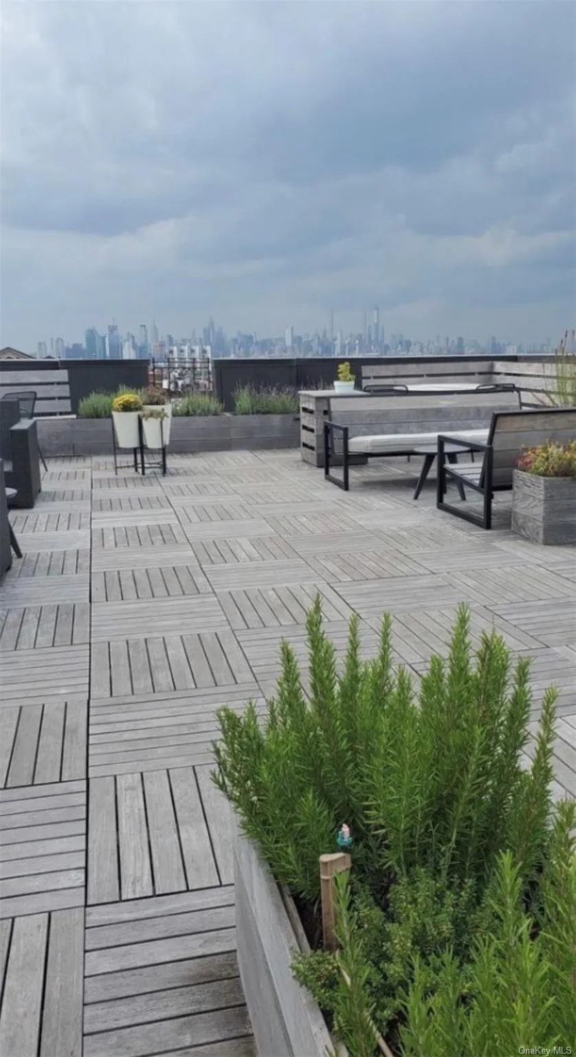 Rooftop terrace with wood plank flooring, elevated planters with greenery, and distant city views Rooftop terrace with wood plank flooring, elevated planters with greenery, and distant city views