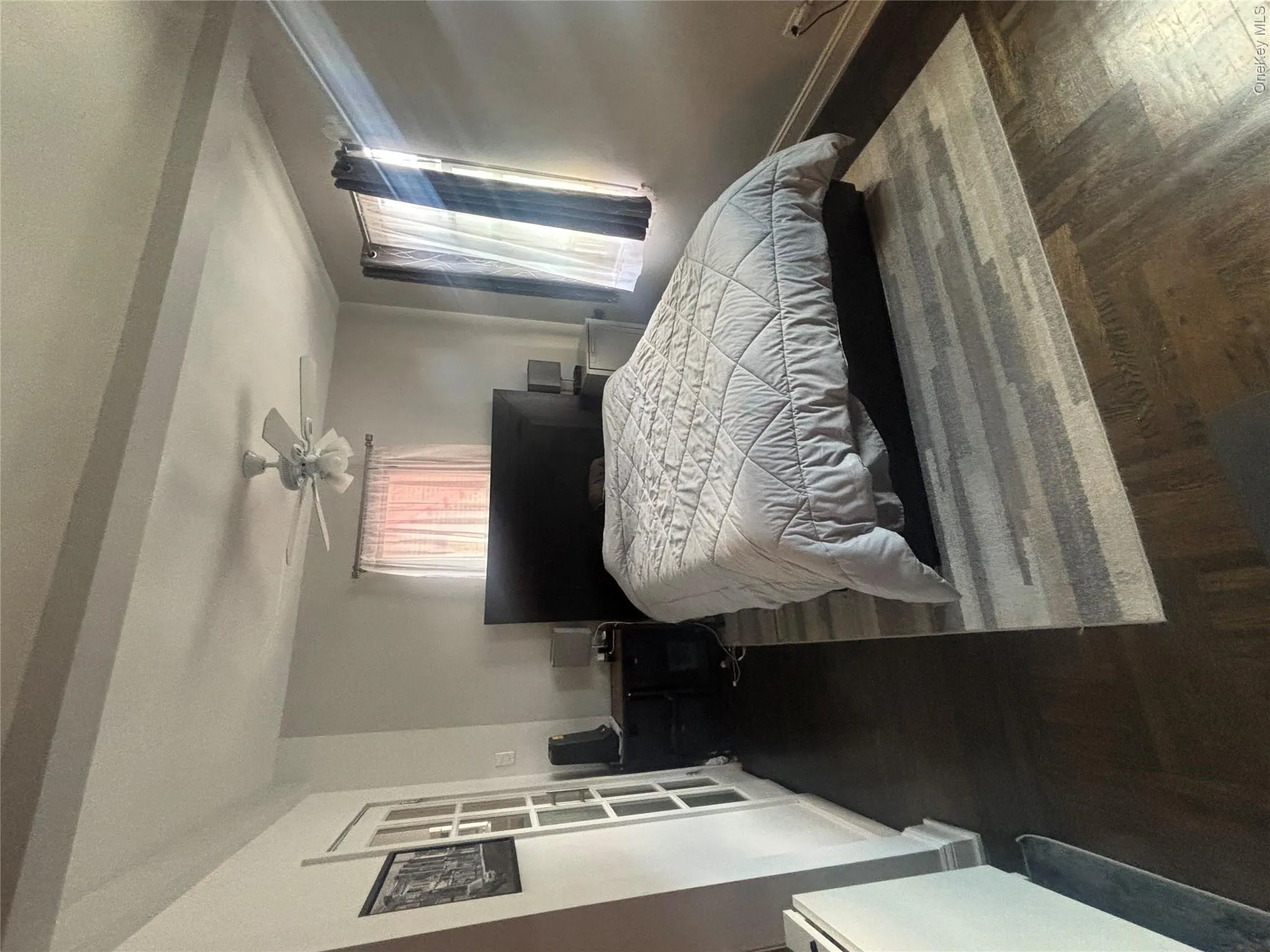 Area of the Studio featuring hardwood floors, a ceiling fan, and windows with drapes Area of the Studio featuring hardwood floors, a ceiling fan, and windows with drapes