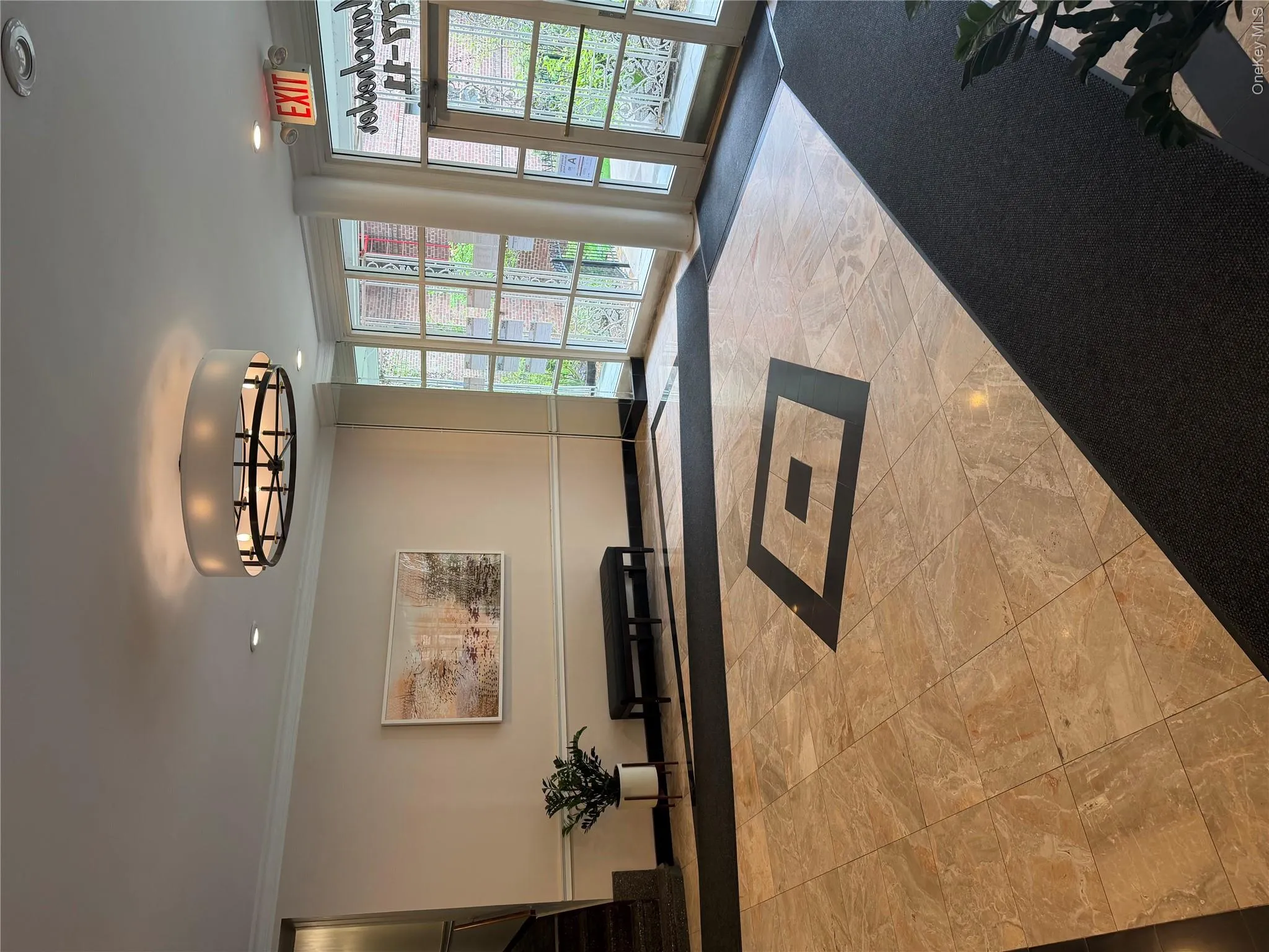 The entrance features polished tile flooring with a decorative inlay, full glass paneled doors, and a modern circular ceiling light fixture The entrance features polished tile flooring with a decorative inlay, full glass paneled doors, and a modern circular ceiling light fixture