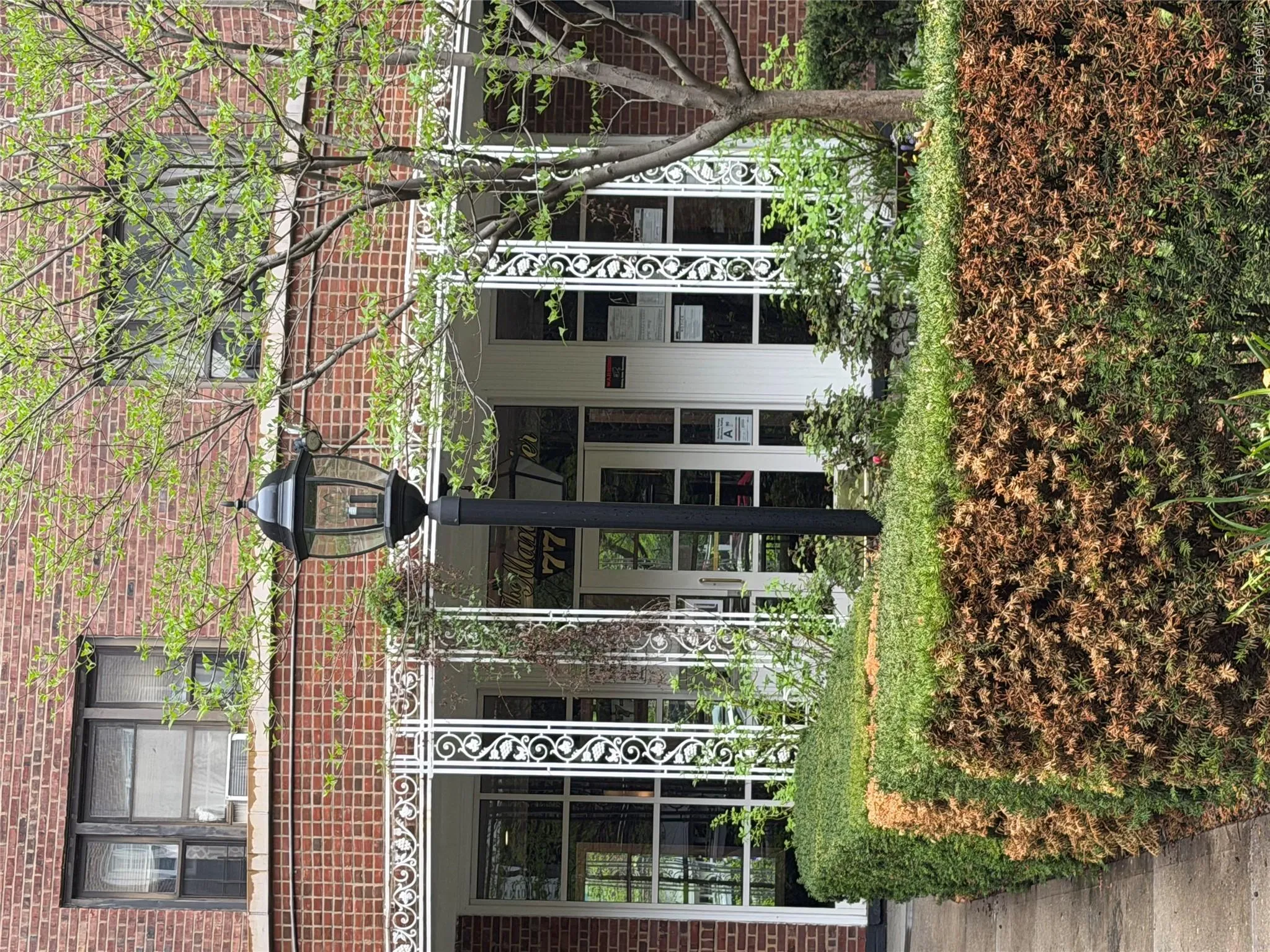 The property features brick construction, decorative white railings, and a prominent exterior lamp post The property features brick construction, decorative white railings, and a prominent exterior lamp post
