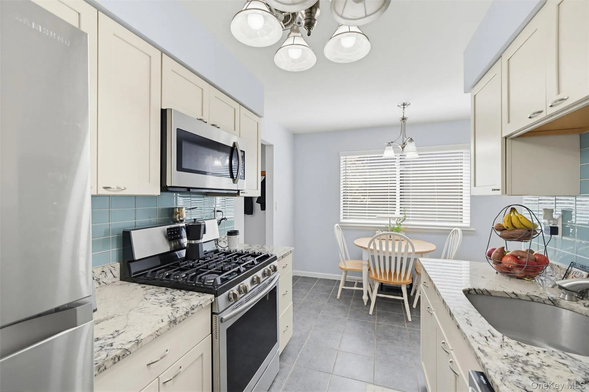 Kitchen featuring light-colored cabinetry, stainless steel appliances, granite countertops, and a subway tile backsplash Kitchen featuring light-colored cabinetry, stainless steel appliances, granite countertops, and a subway tile backsplash