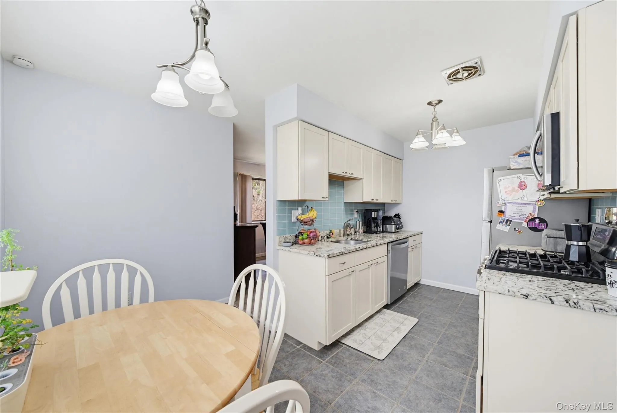 The kitchen features light-colored cabinetry, a tile backsplash, and granite countertops The kitchen features light-colored cabinetry, a tile backsplash, and granite countertops