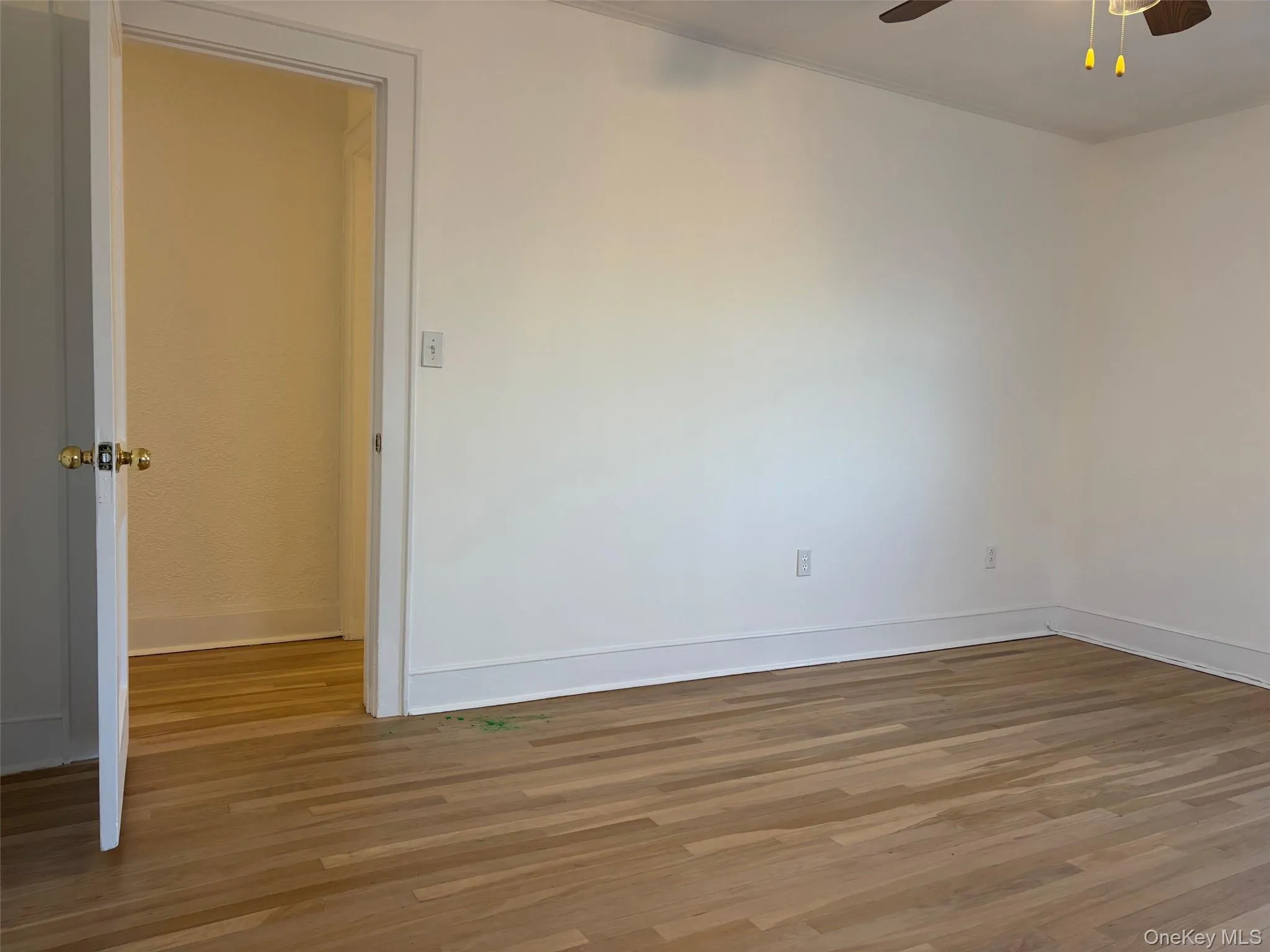 Interior room featuring light hardwood floors, white walls, and a ceiling fan Interior room featuring light hardwood floors, white walls, and a ceiling fan