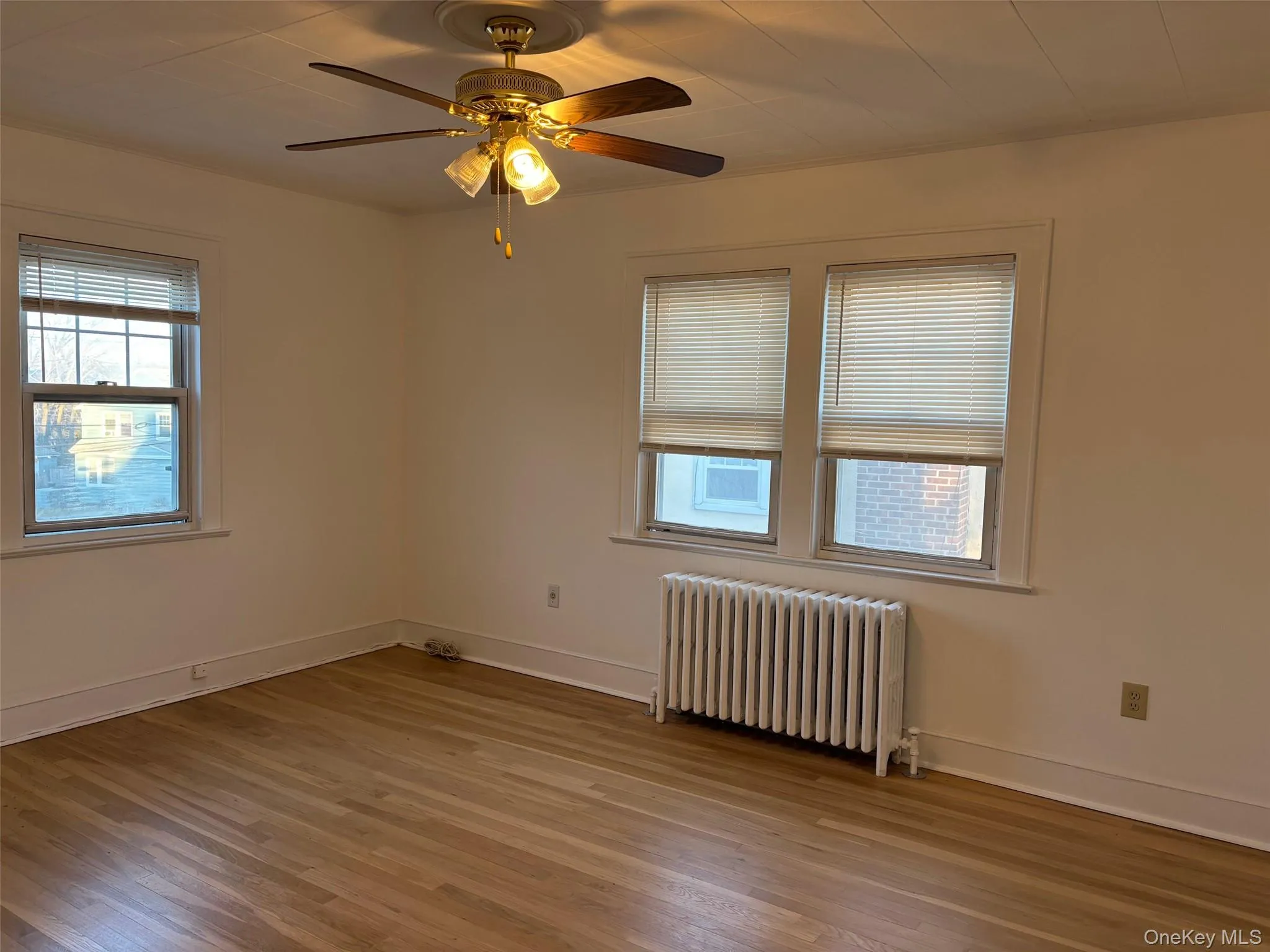 The room features hardwood floors, white walls, and a ceiling fan with integrated lighting The room features hardwood floors, white walls, and a ceiling fan with integrated lighting