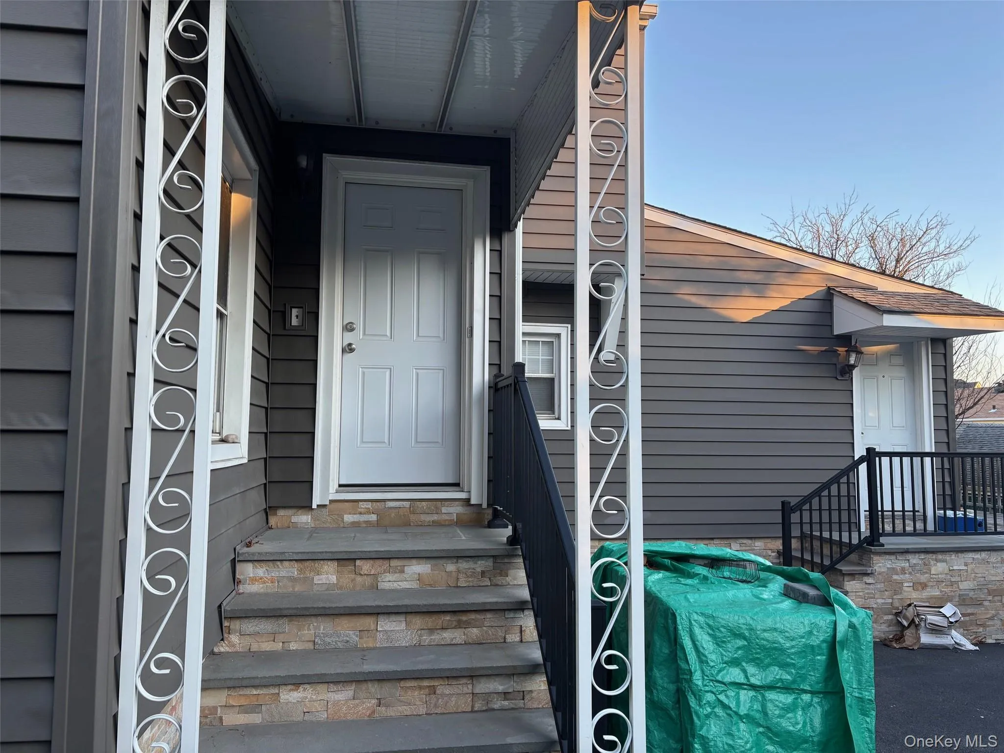 Property exterior featuring grey siding and an entry with stone-clad steps Property exterior featuring grey siding and an entry with stone-clad steps