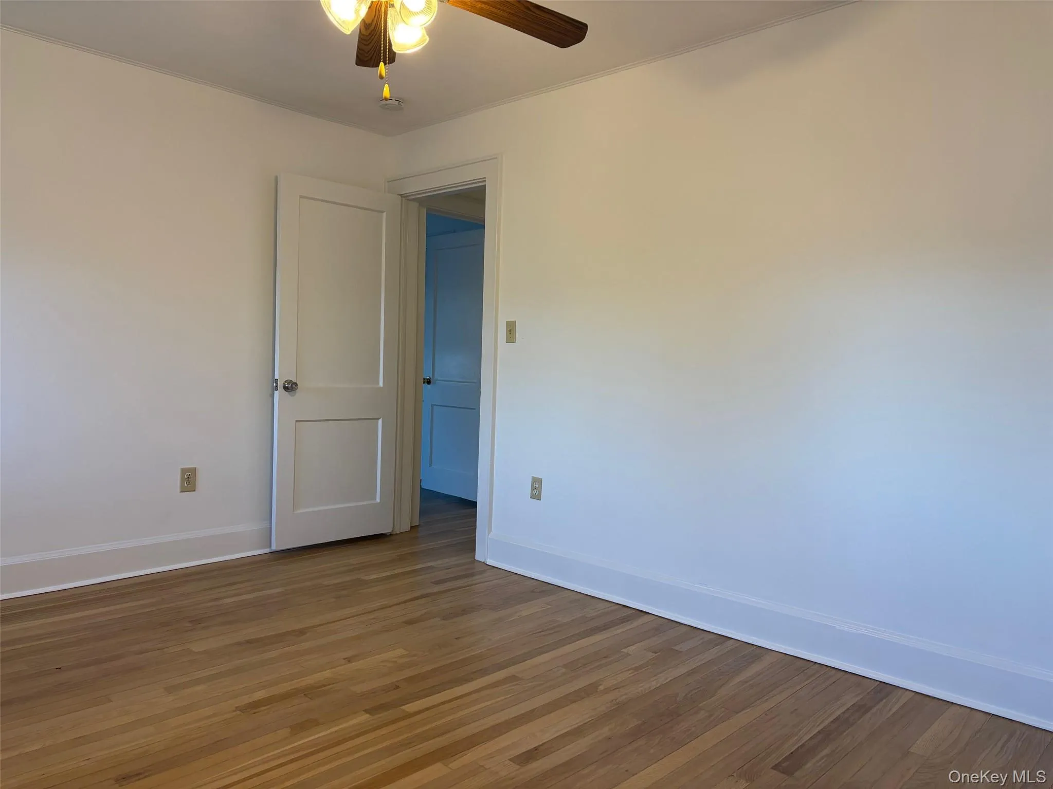 Room with hardwood flooring, a ceiling fan, and white painted walls Room with hardwood flooring, a ceiling fan, and white painted walls